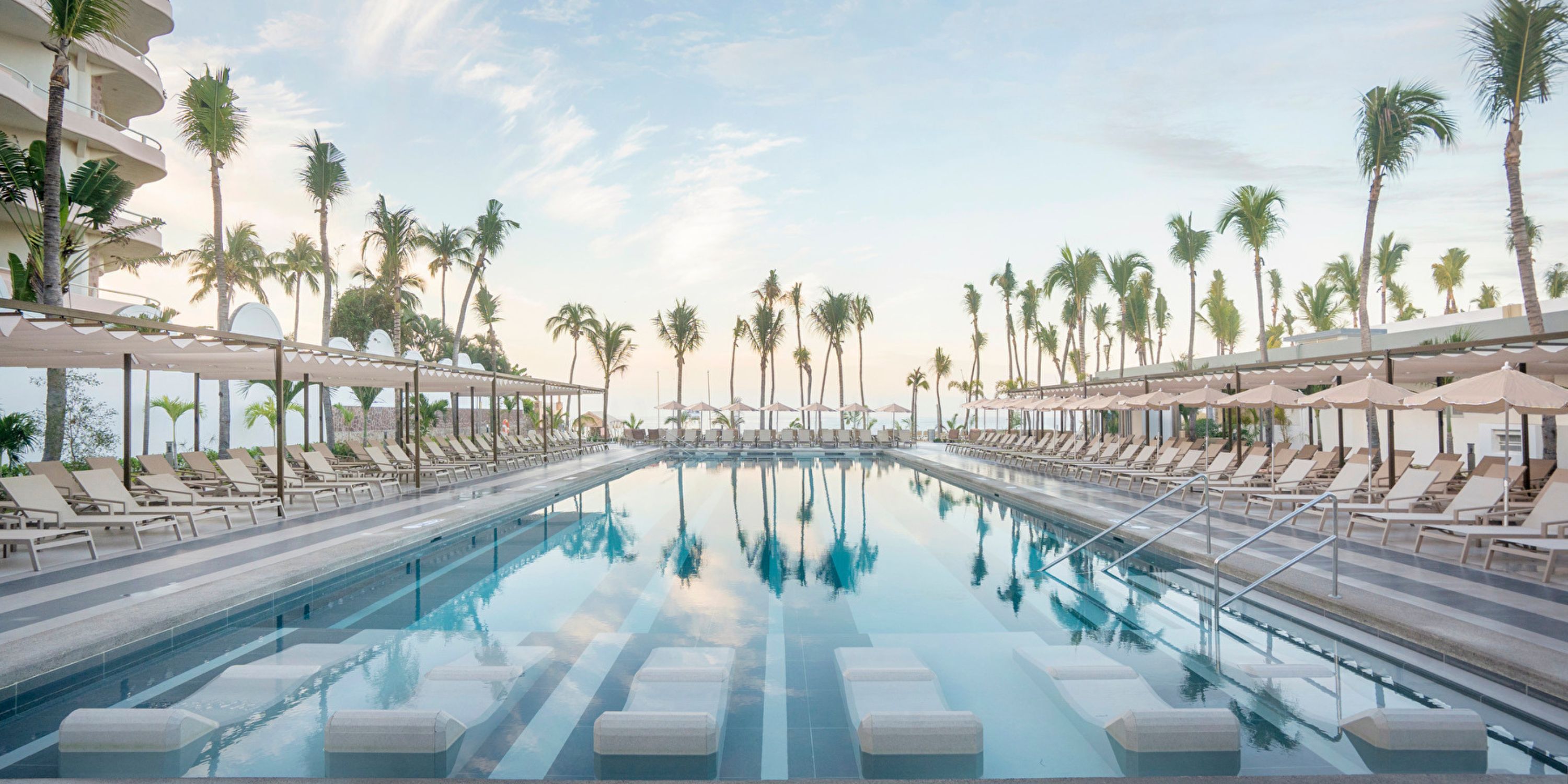 Hotel Riu Jalisco&rsquo;s outdoor pool with lounge chairs and palm trees is perfect for a destination wedding.