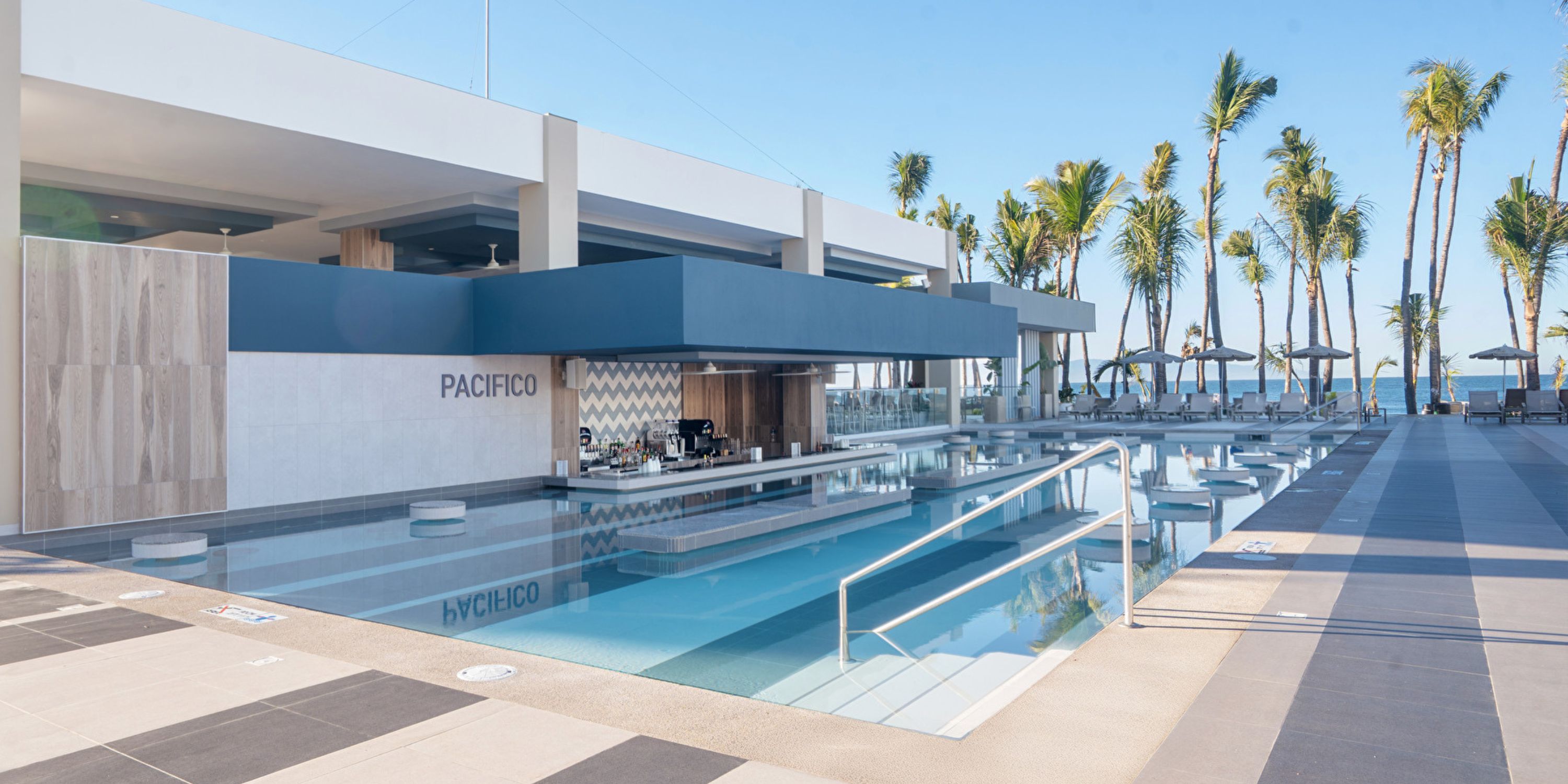 Hotel Riu Jalisco: poolside bar with modern seating, palm trees, ocean views&mdash;ideal for a destination wedding.