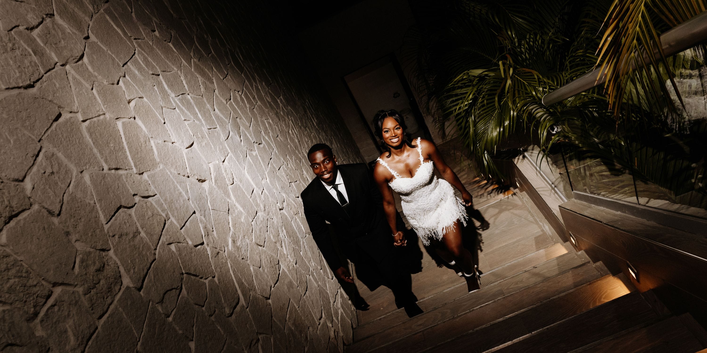 Quishona and Delon (Copy) feature a wedding couple in formal attire on a stone staircase with a potted plant.