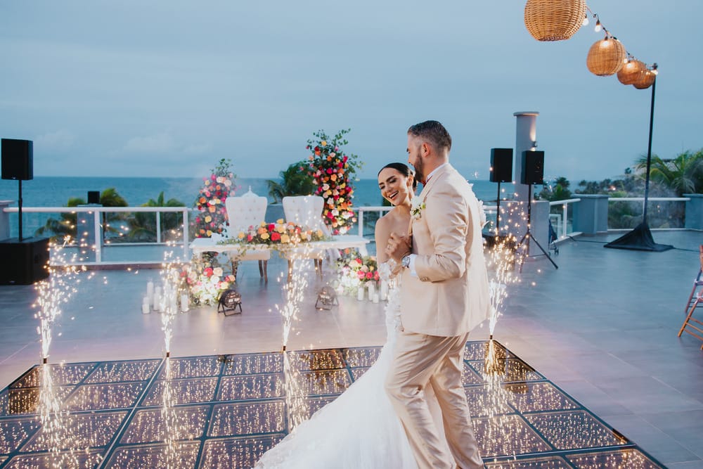 Newlyweds dance surrounded by sparklers on a beautifully decorated terrace at their destination wedding.