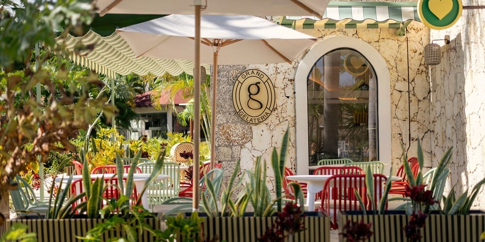 Charming outdoor cafe with red and green chairs, ideal for a destination wedding, awning, and greenery.