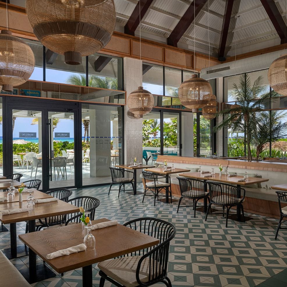 Chic restaurant with wooden tables, black chairs, and woven lights&mdash;perfect for a destination wedding.