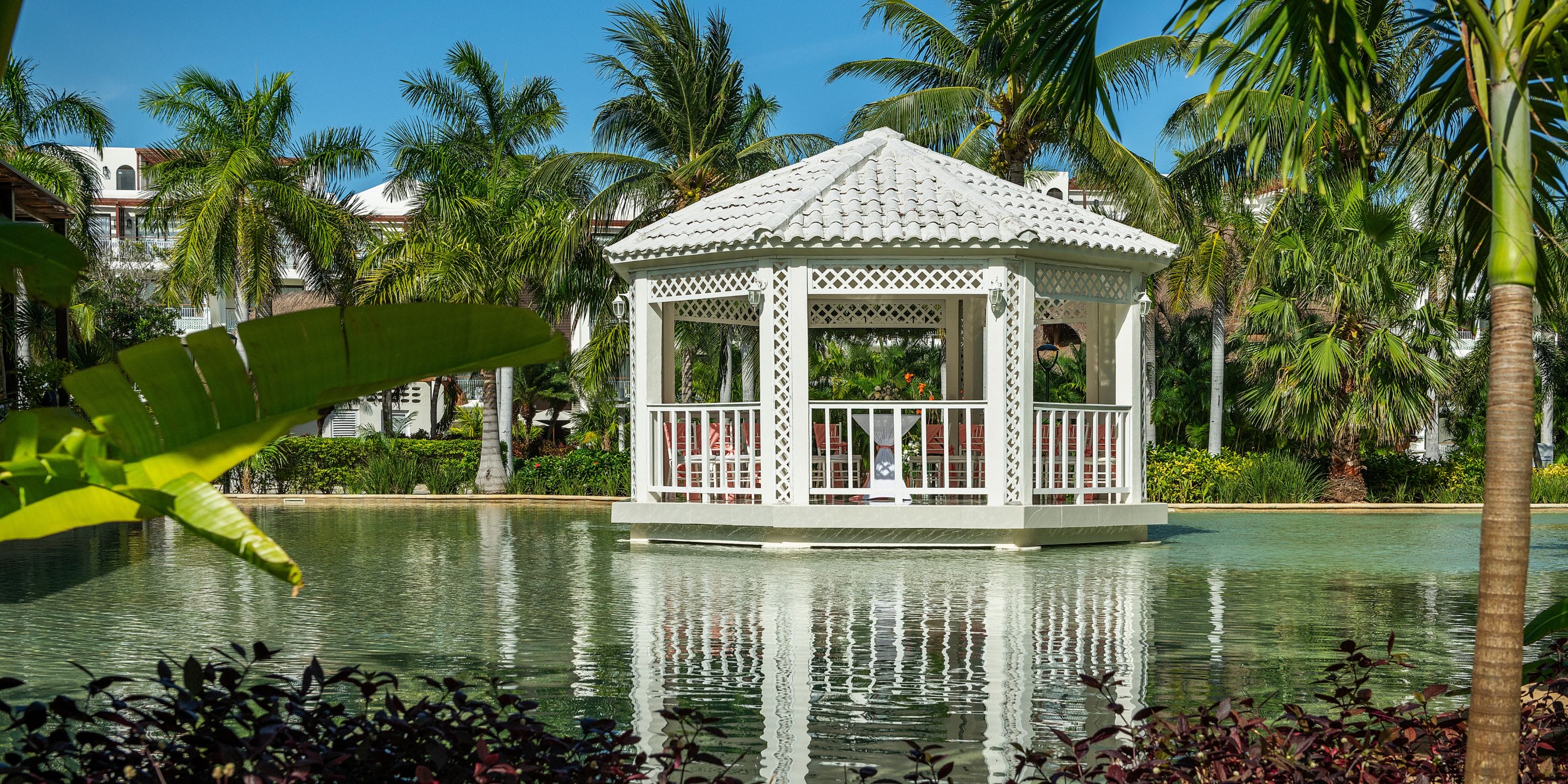 Ocean Riviera Paradise gazebo by a pond, surrounded by palms&mdash;an ideal spot for a destination wedding.
