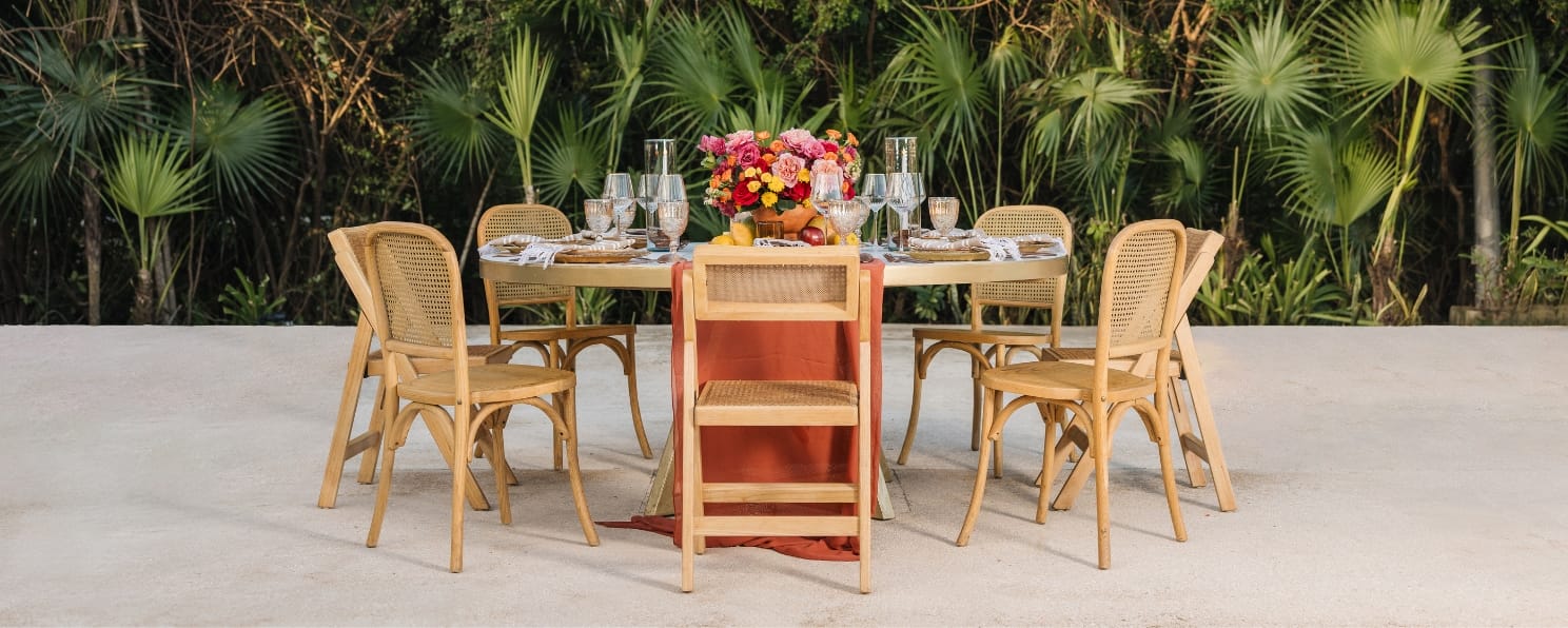 Round outdoor table for six with wooden chairs, floral centerpiece, glassware&mdash;destination wedding.
