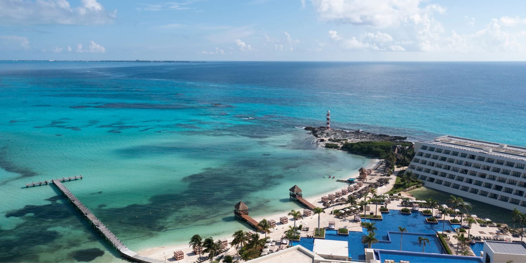 Aerial view of a beachfront resort, perfect for a destination wedding, with pools, pier, and turquoise ocean.