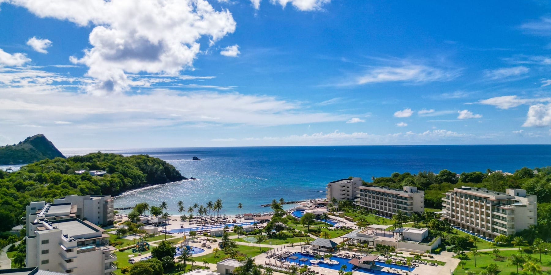 Aerial view of a beachfront resort perfect for a destination wedding, with pools, palms, and ocean.