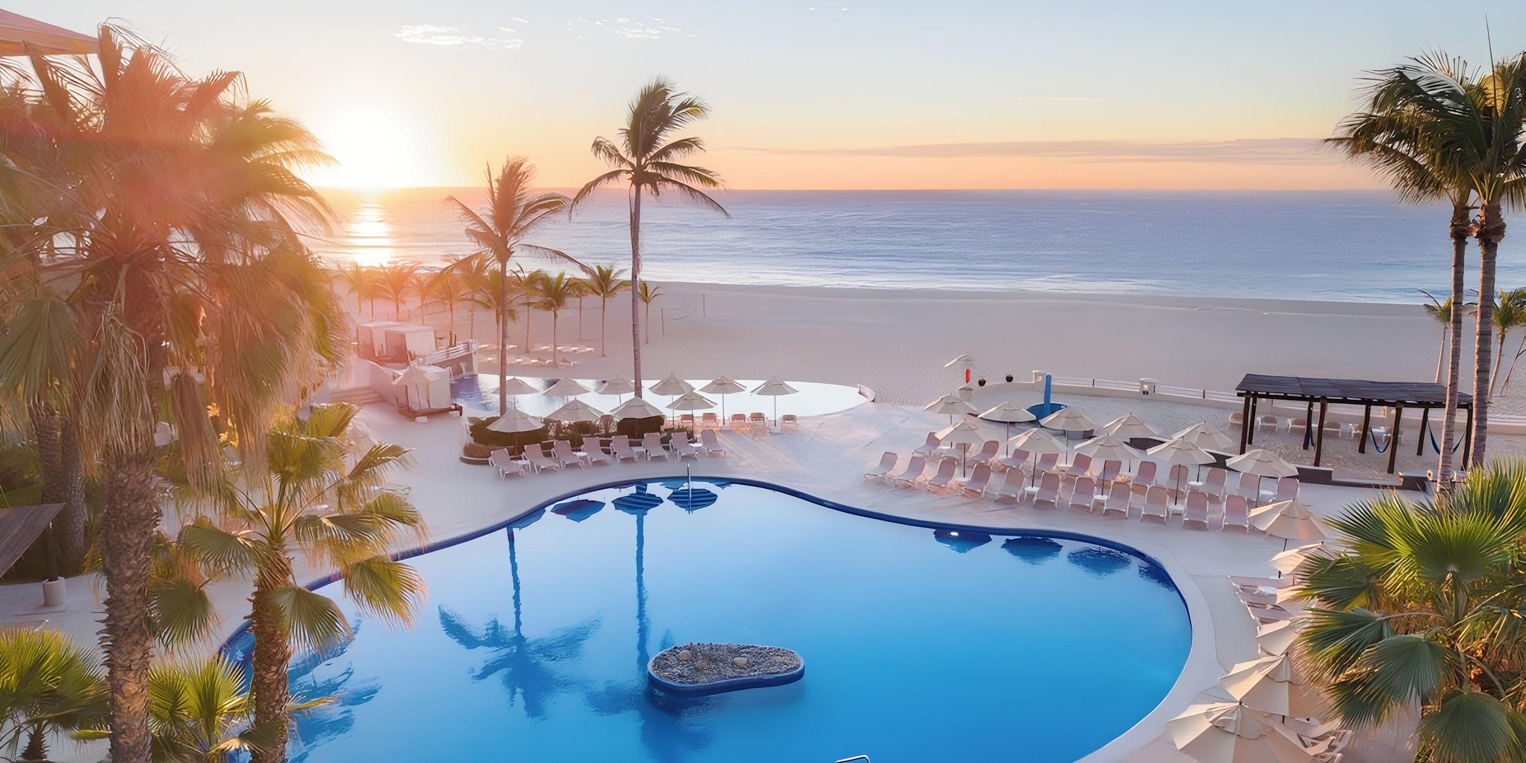 Barcel&oacute; Grand Faro Los Cabos pool, lounge chairs, and palm trees&mdash;perfect for a destination wedding sunrise.