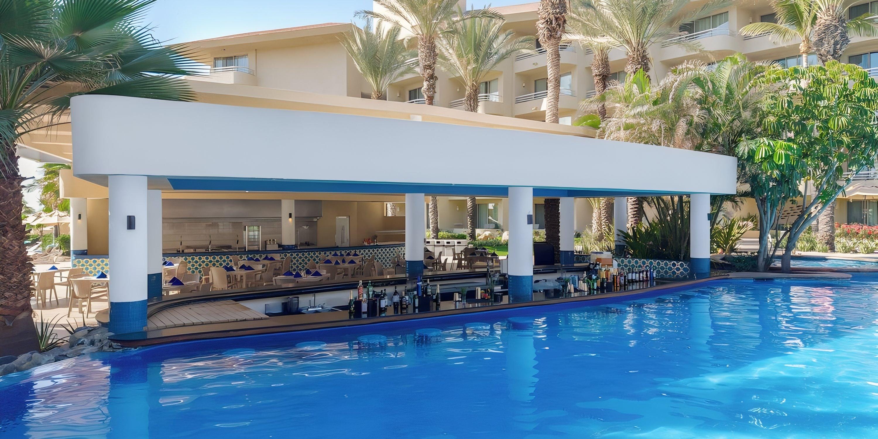 Barcel&oacute; Grand Faro Los Cabos: Pool swim-up bar, palm trees, hotel&mdash;ideal for a destination wedding.