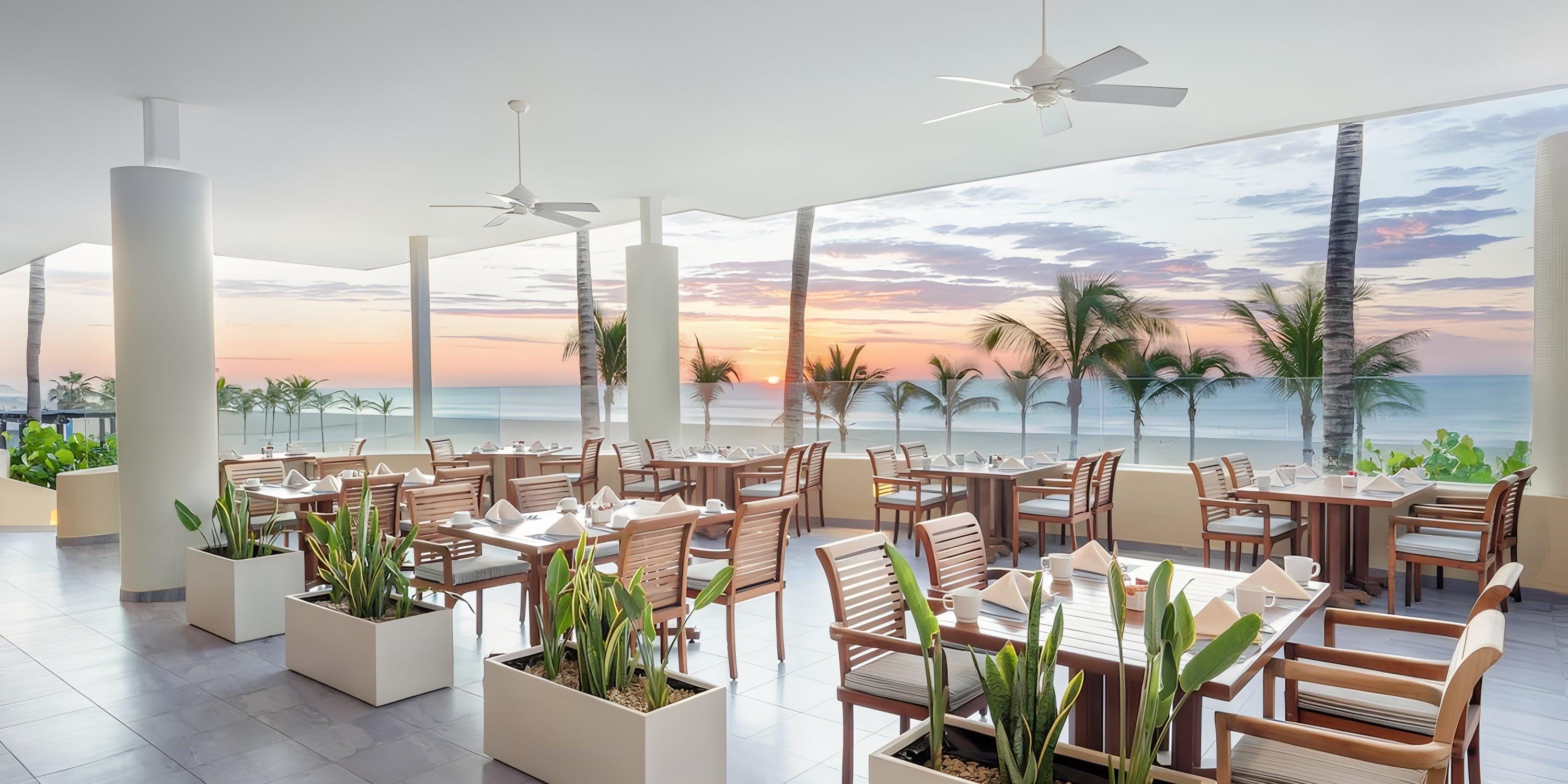Barcel&oacute; Grand Faro Los Cabos: open-air dining with wooden tables and sunset views for destination weddings.
