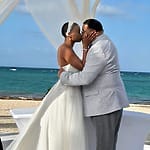 Bride and groom kiss during a picturesque outdoor destination wedding ceremony on the beach.