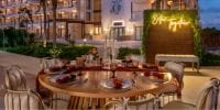 Elegant outdoor wedding dining table set near a hotel, featuring a neon "Better Together" sign.