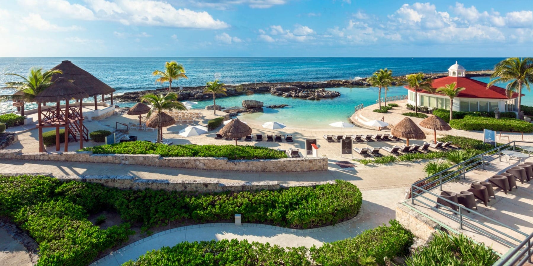 Beachfront resort set for a destination wedding, with lounge chairs, palm trees, and ocean views.