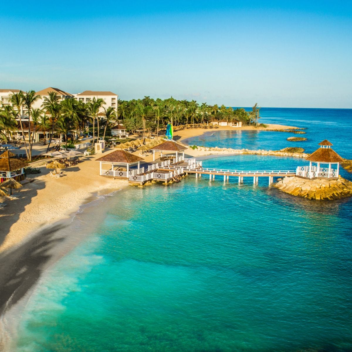 Aerial view of a tropical beach resort, perfect for a destination wedding, with clear blue water and palms.