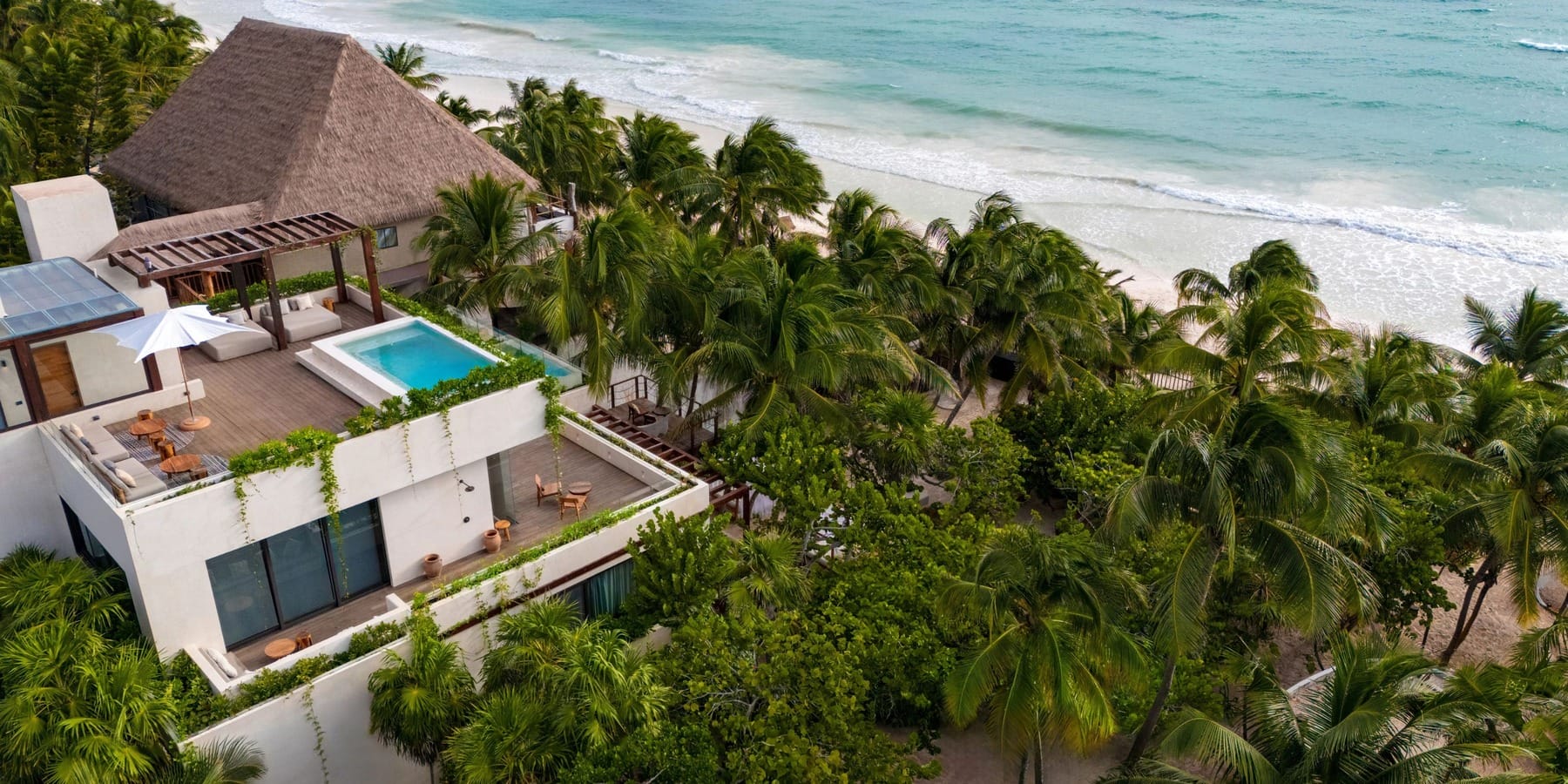 A modern beachfront villa with a rooftop pool and palm trees, perfect for a destination wedding by the ocean.