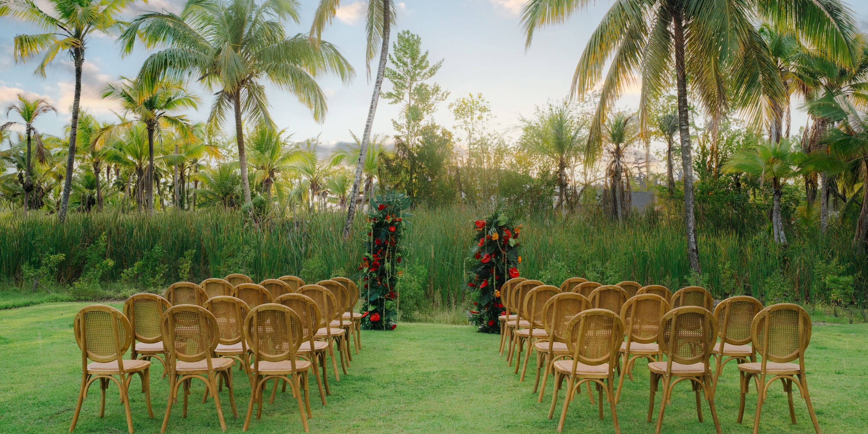 Chairs set up for a destination wedding face a floral arch outdoors at Zemi Miches Punta Cana Resort.