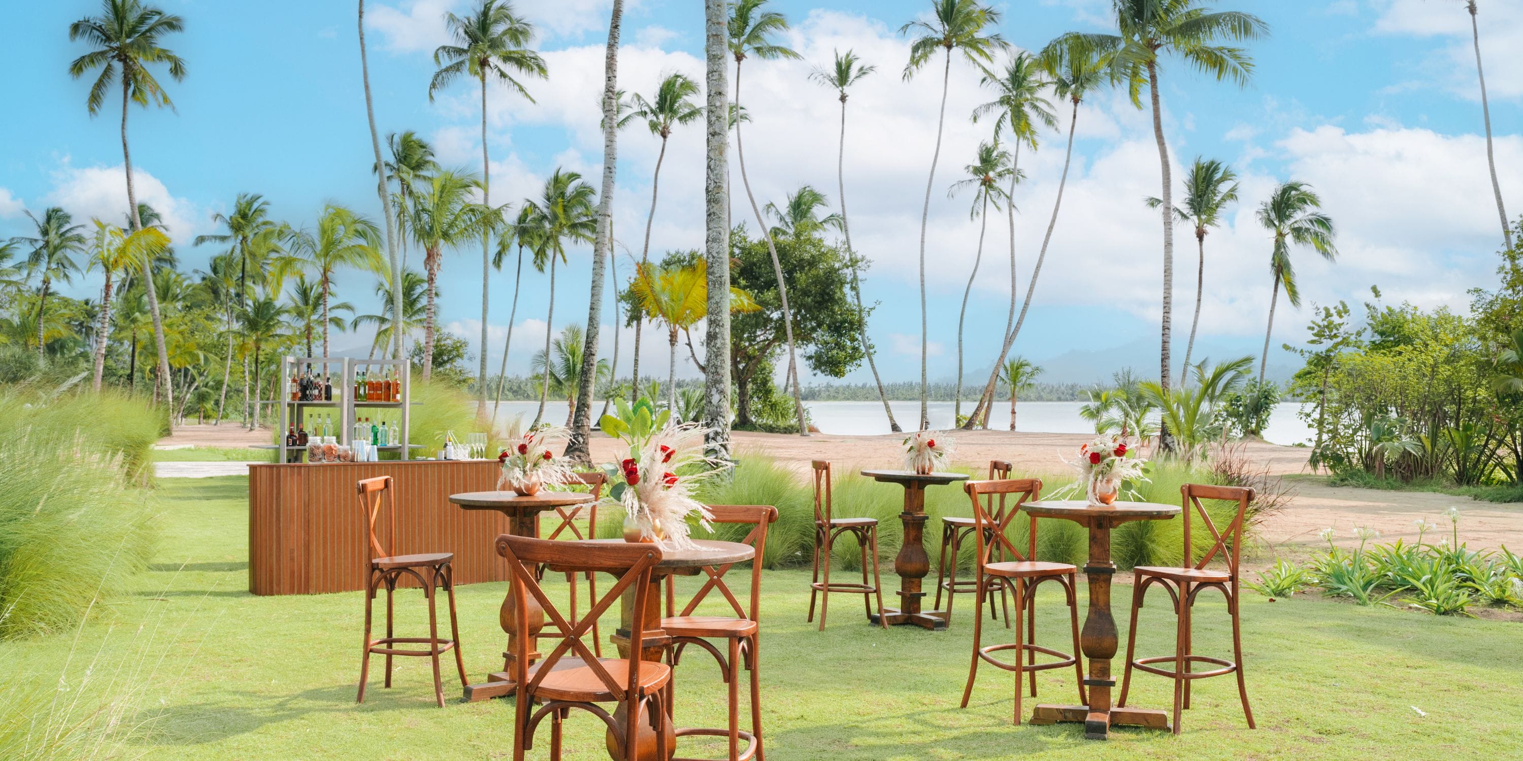 Scenic outdoor seating with wooden tables and chairs on grass, perfect for a destination wedding setting.