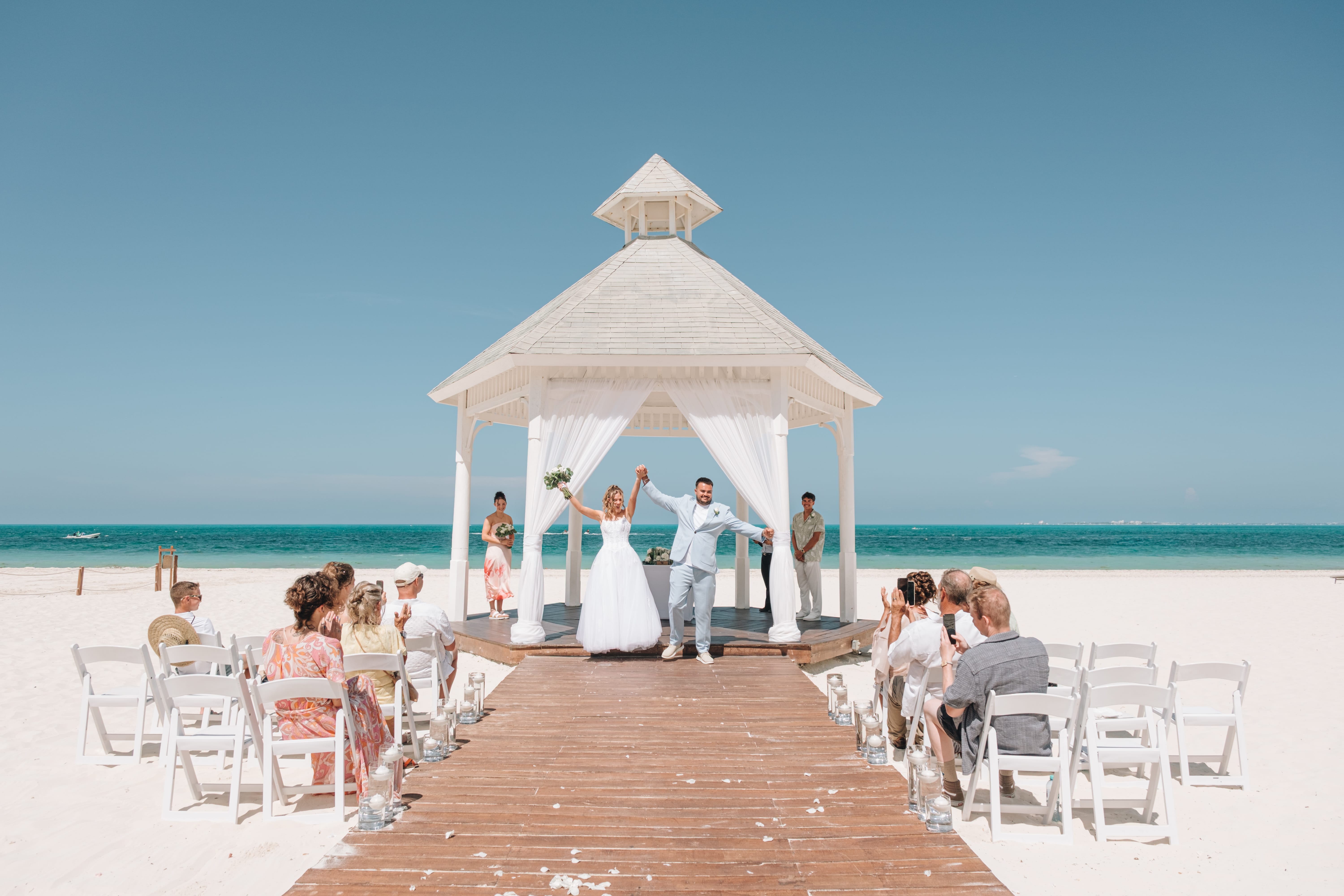 Kayleigh and Isaac’s destination wedding: couple marries under a white gazebo on a sunny beach.