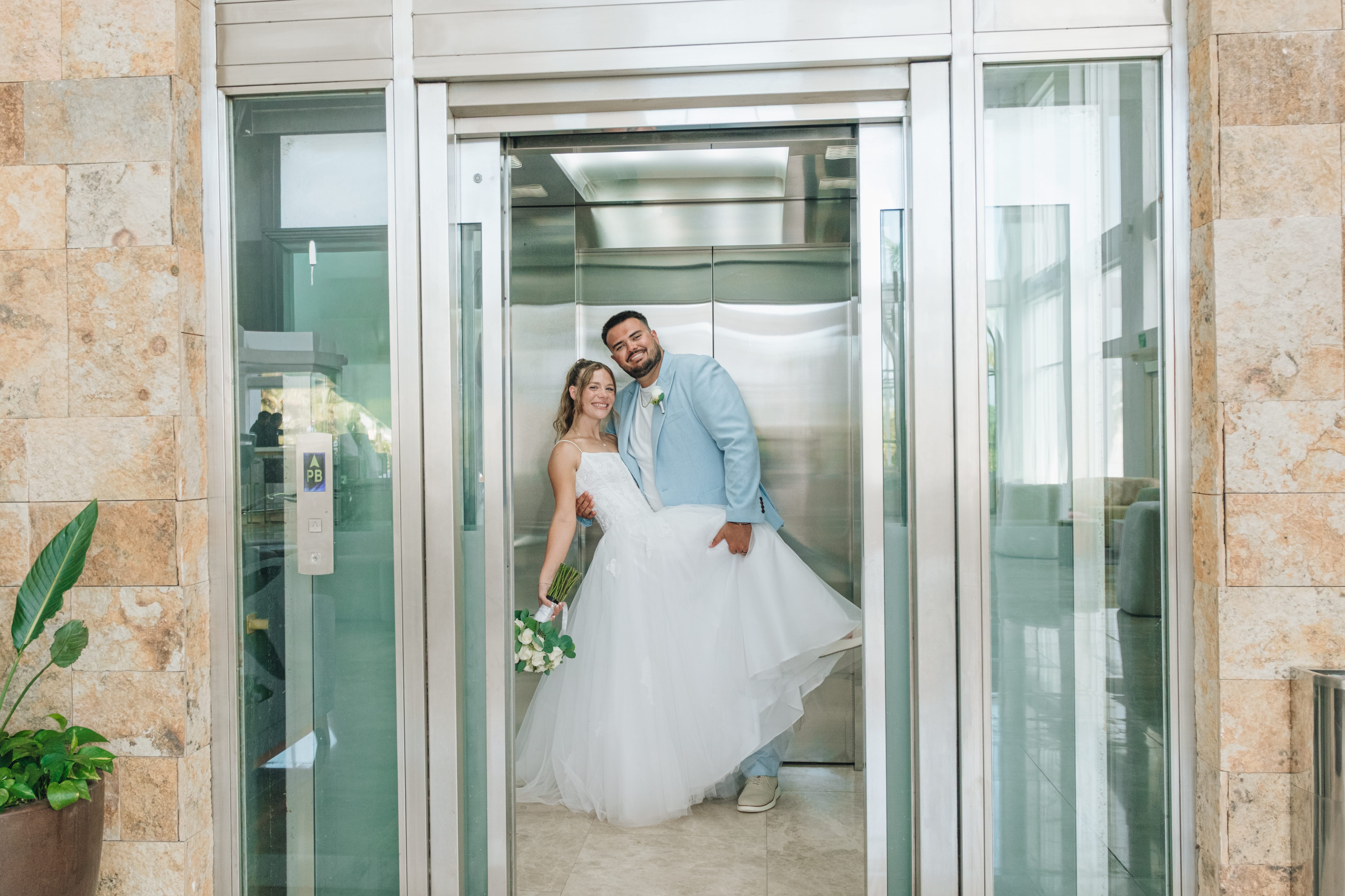 Bride and groom smiling together in an open elevator at Kayleigh and Isaac's destination wedding.