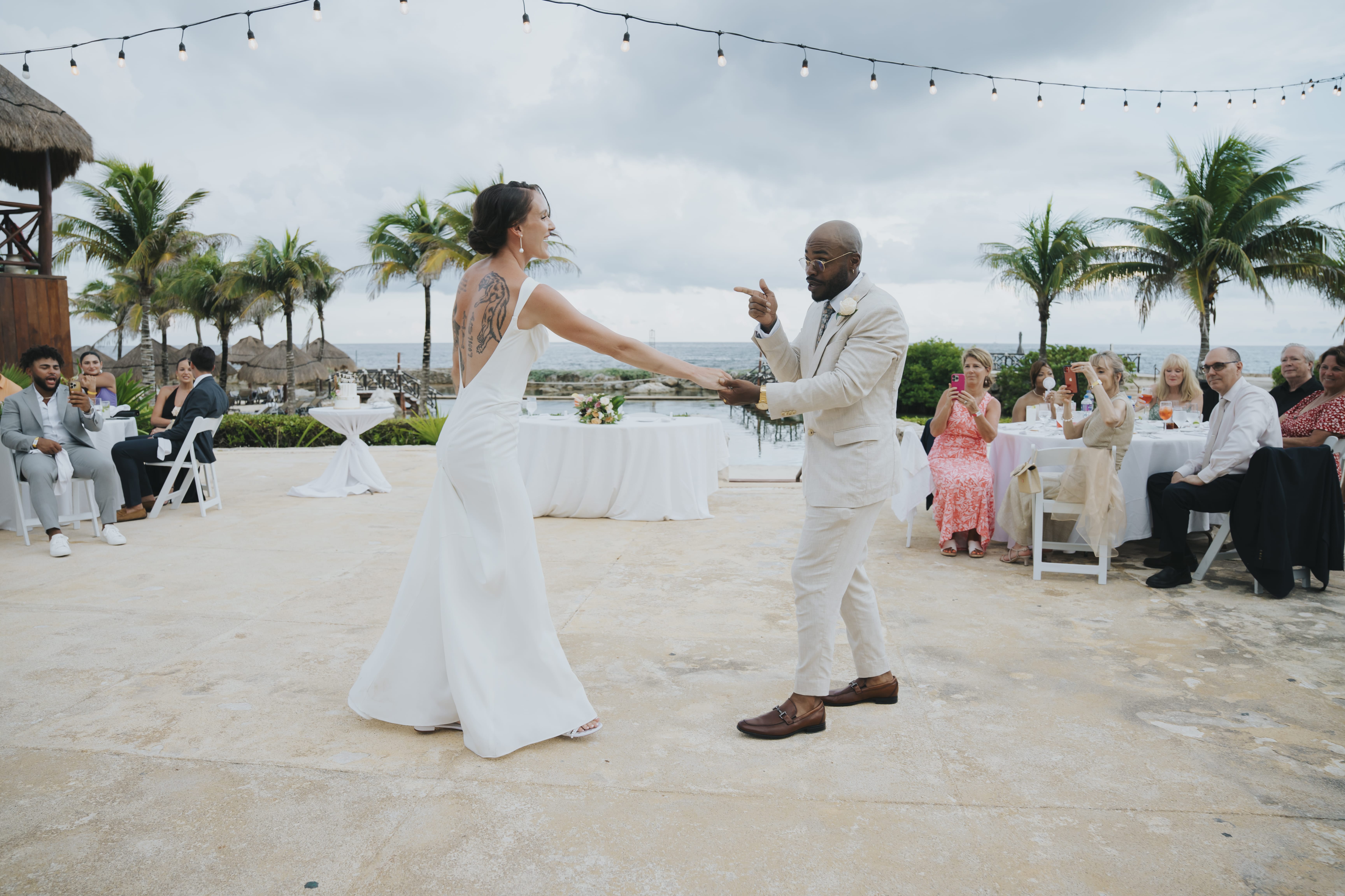 Madison and Blake share a dance at their destination wedding as guests look on from outdoor tables.