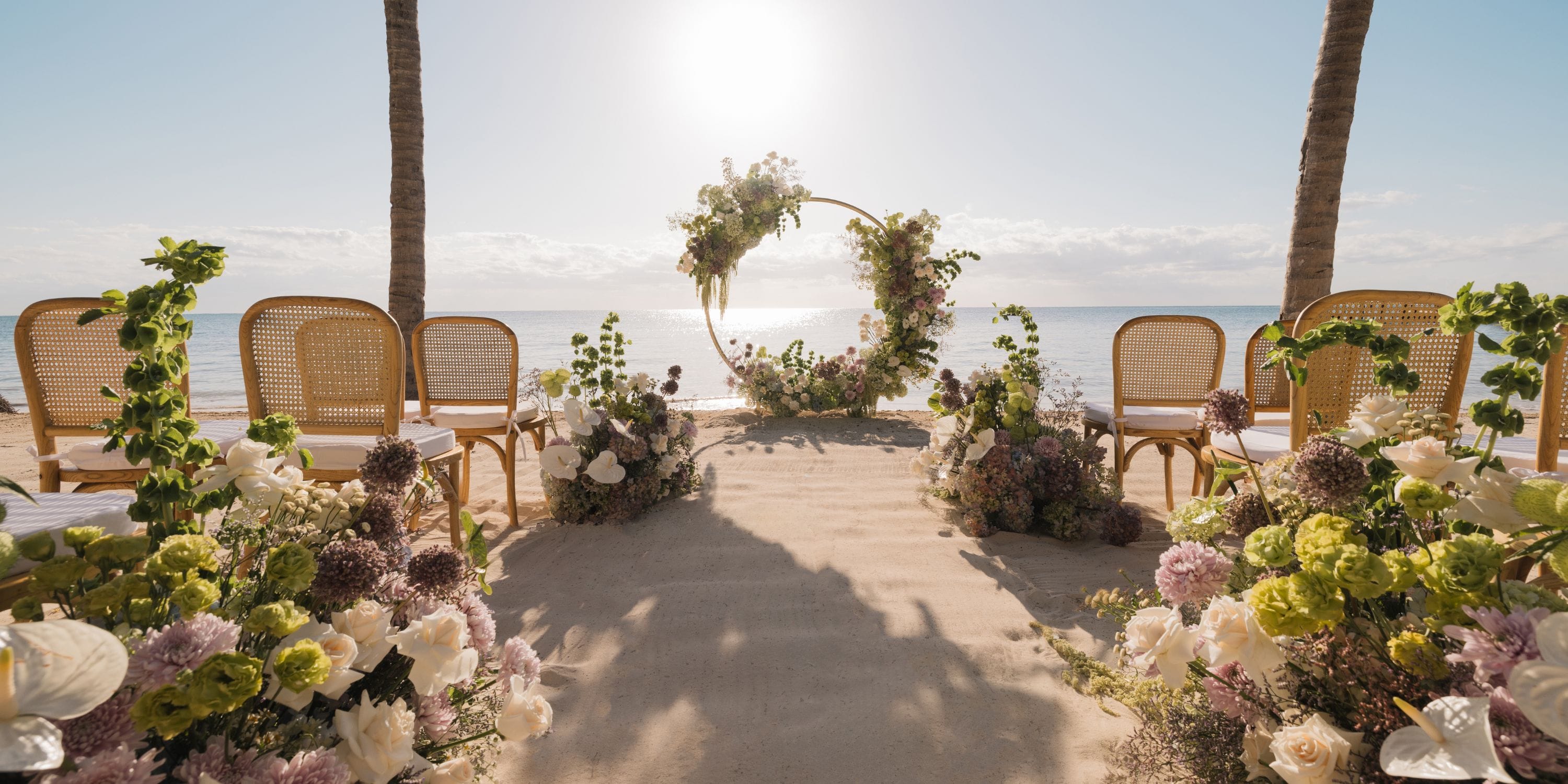 Destination wedding at Royalton Riviera Cancun with floral arch, ocean view, and elegant seating.