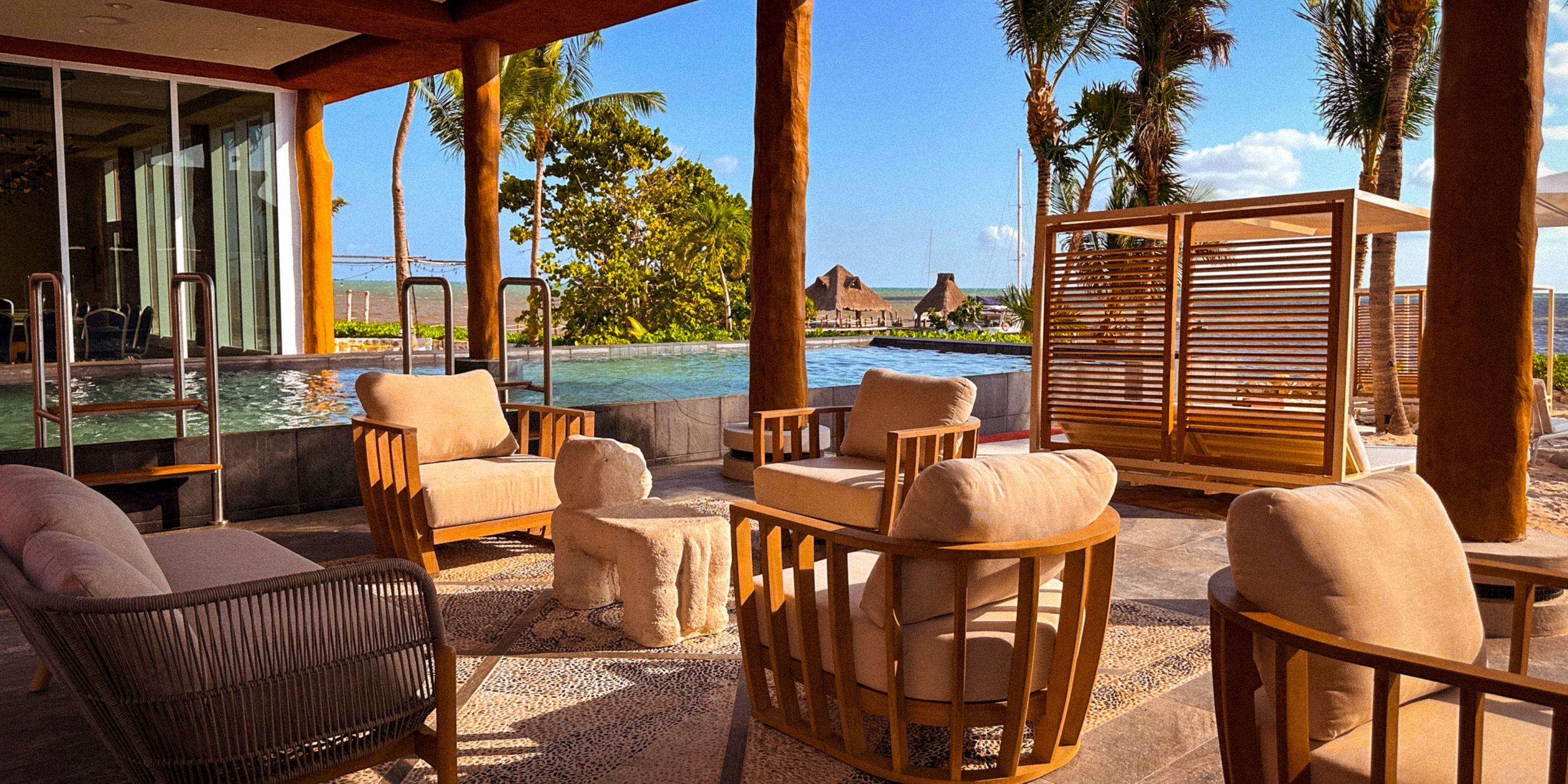 Poolside lounge at a destination wedding in Royalton Riviera Cancun, framed by palms and sunshine.