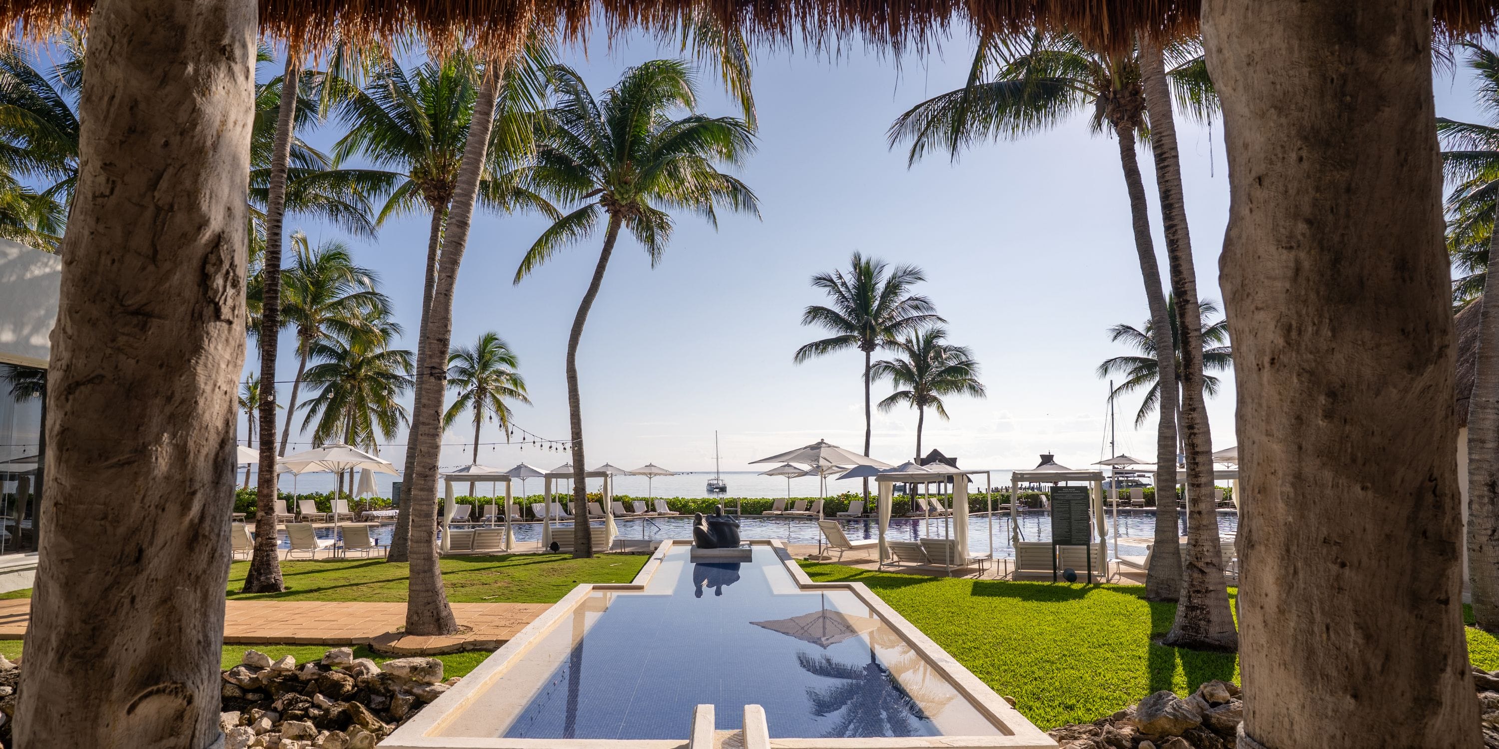 Palm-lined pool guides guests to Royalton Riviera Cancun, a perfect destination wedding oasis.