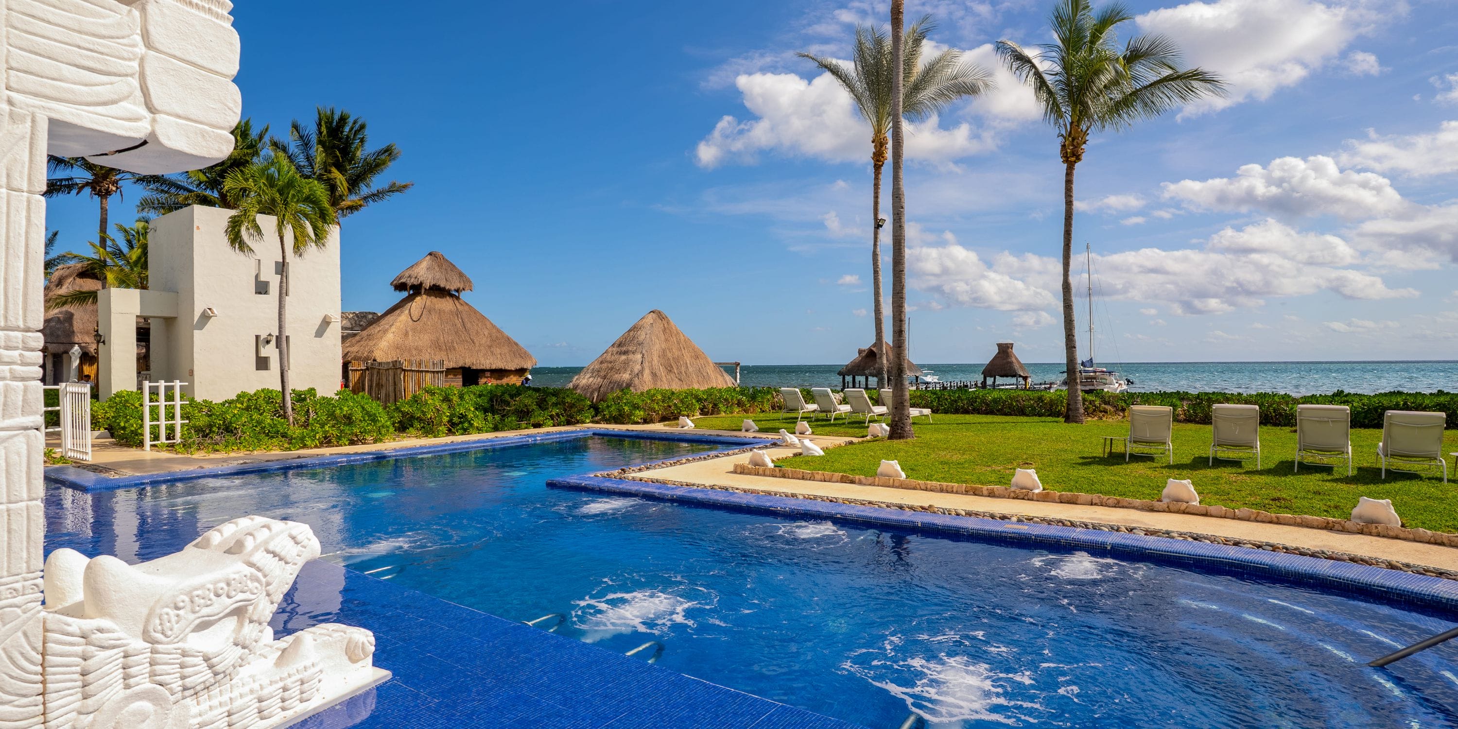 Blue-tiled pool, bubbling jets, palm trees, and ocean&mdash;an ideal Royalton destination wedding spot.