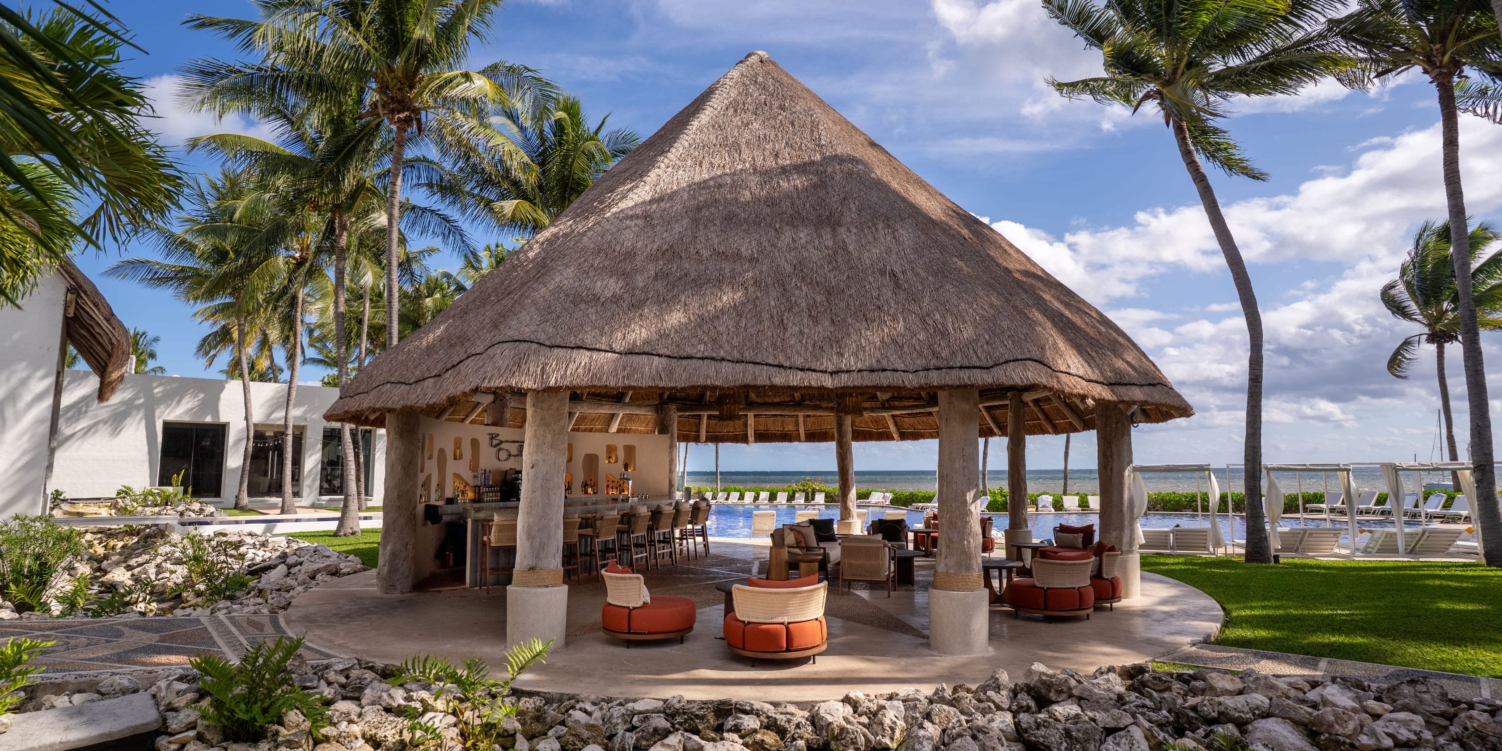 Thatched-roof bar, seating, palm trees, ocean views&mdash;ideal for a Royalton Riviera Cancun wedding.
