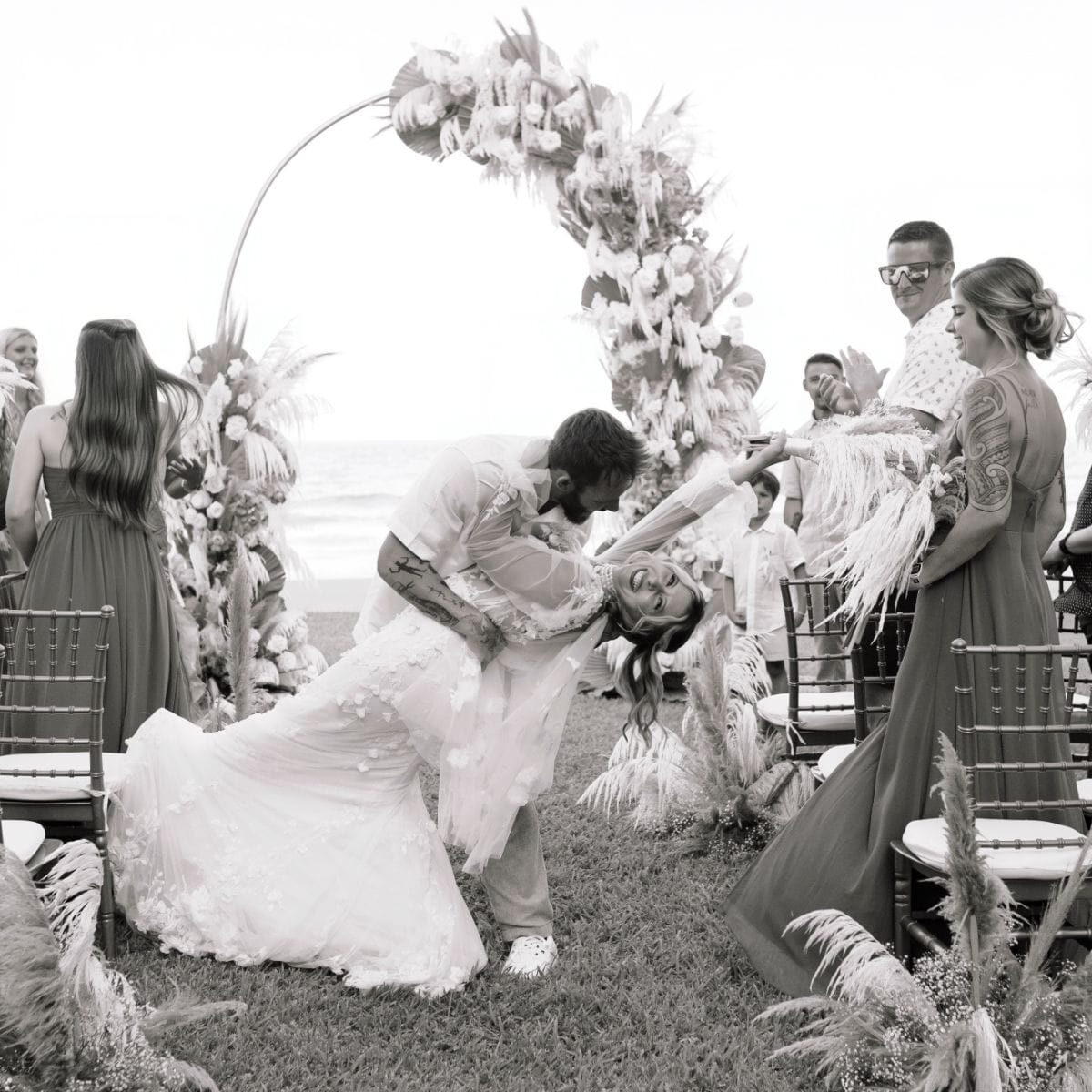 Kayleigh and Isaac share a dance at their destination wedding, guests and flowers around them.