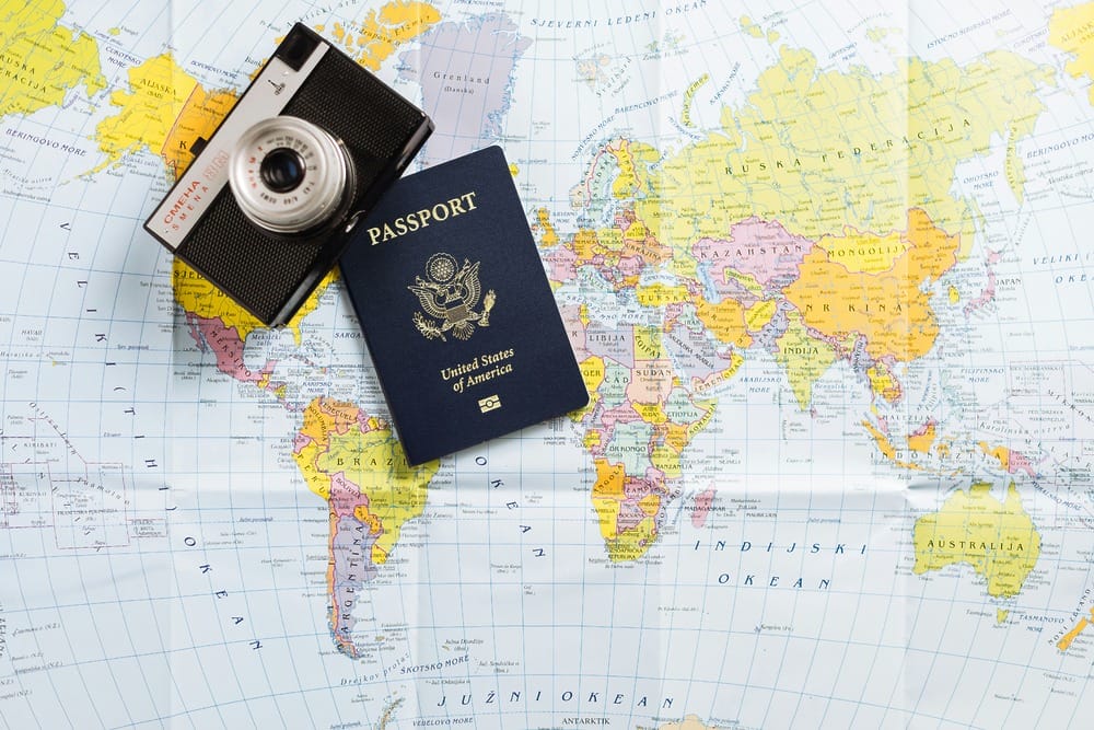 A U.S. passport and camera rest on a world map, perfect for planning a destination wedding.