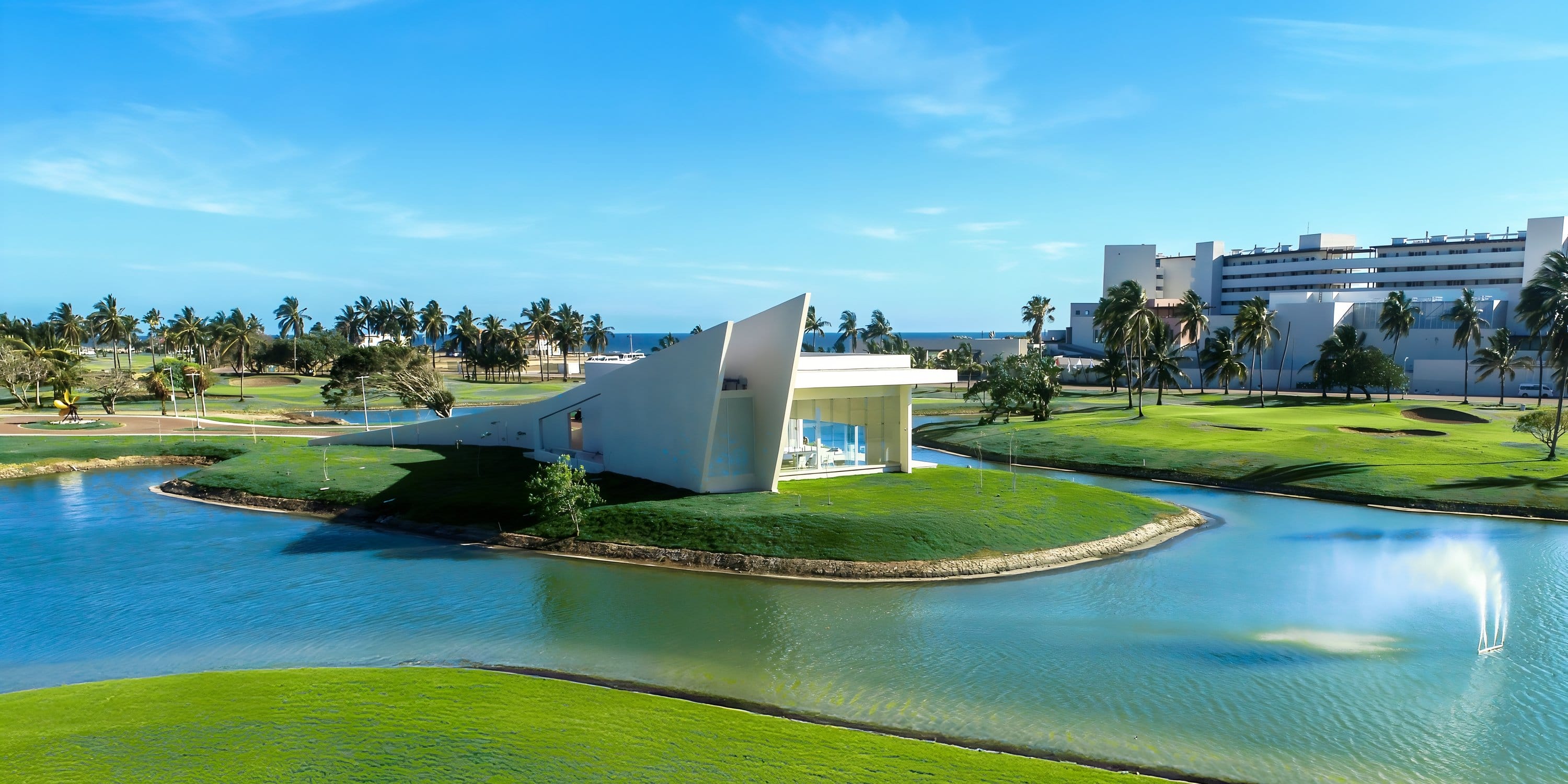 Modern white building on a pond island, perfect for a destination wedding, with resort and palms.