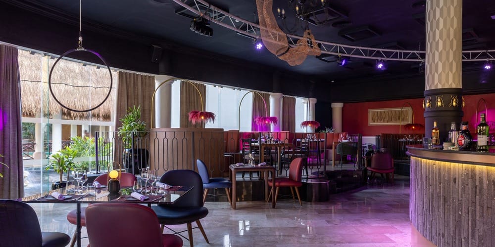 Modern restaurant set for a destination wedding, colorful chairs, set tables, and bright windows.