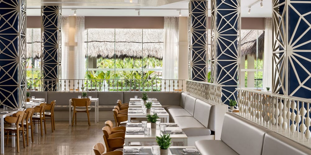 Modern restaurant with white tables, wooden chairs, and large windows&mdash;perfect for a wedding.