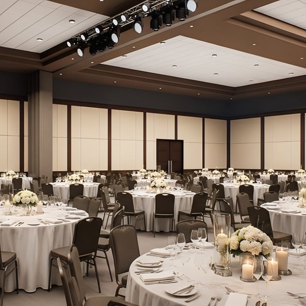 Ballroom set for destination wedding with round tables, white linens, flowers, and empty chairs.