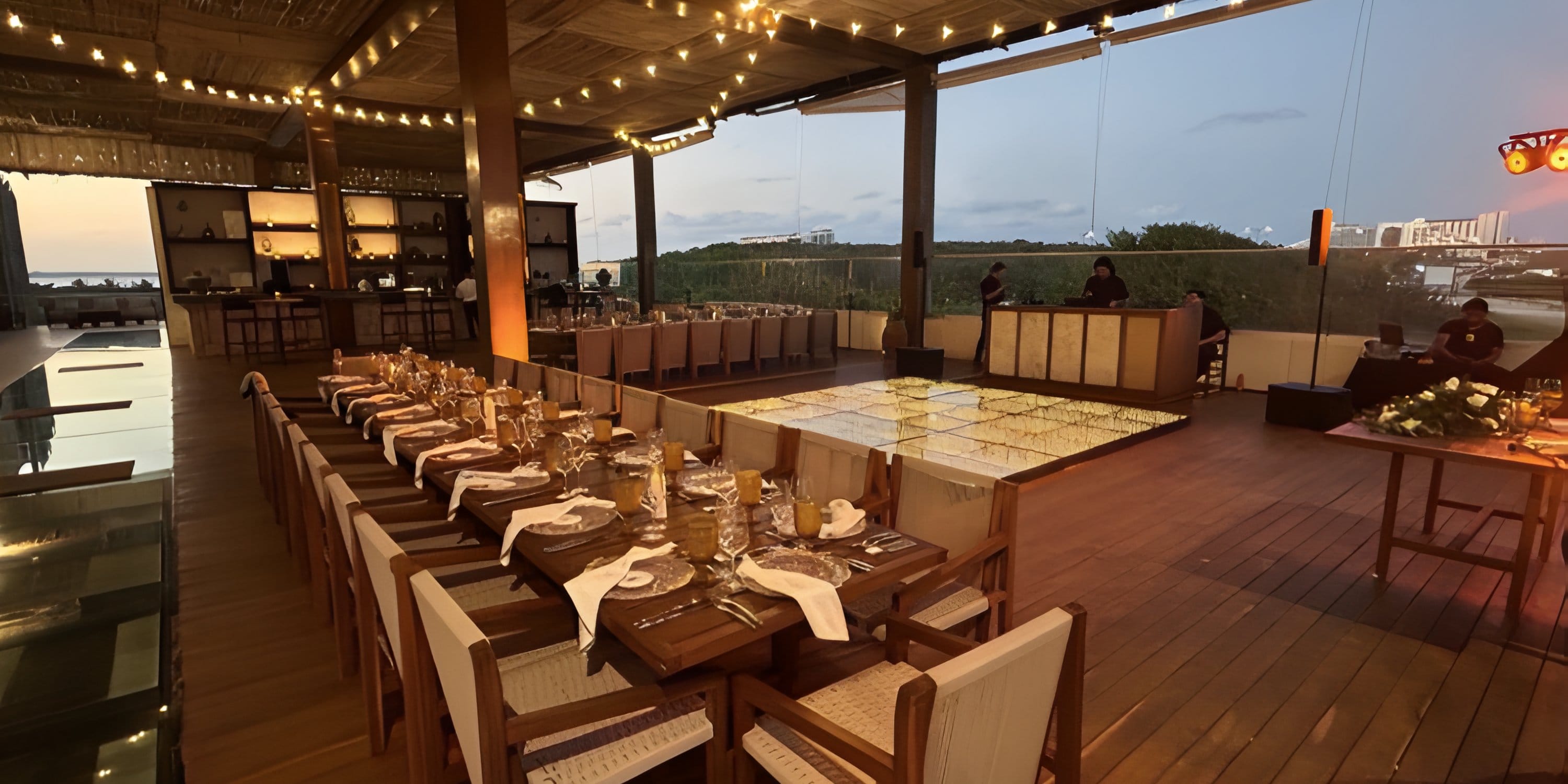 Outdoor wedding reception with long tables and a lit dance floor at Mondrian Cancun All Inclusive.
