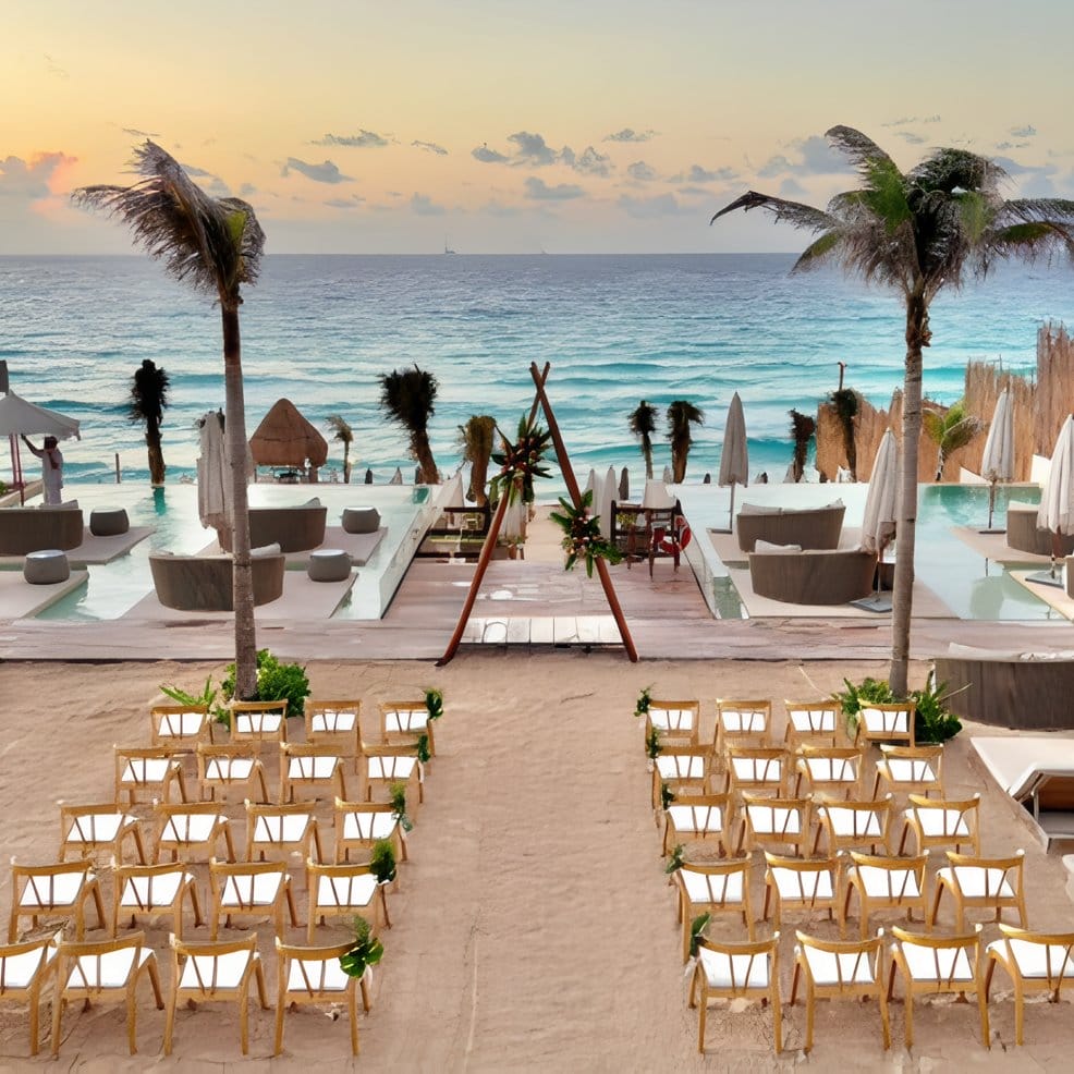 Rows of chairs set up on the sand for a destination wedding by the ocean.