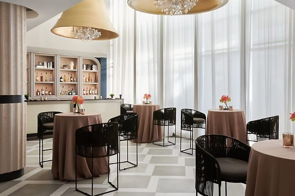 Small tables with pink tablecloths and black chairs for a Mondrian Cancun destination wedding.