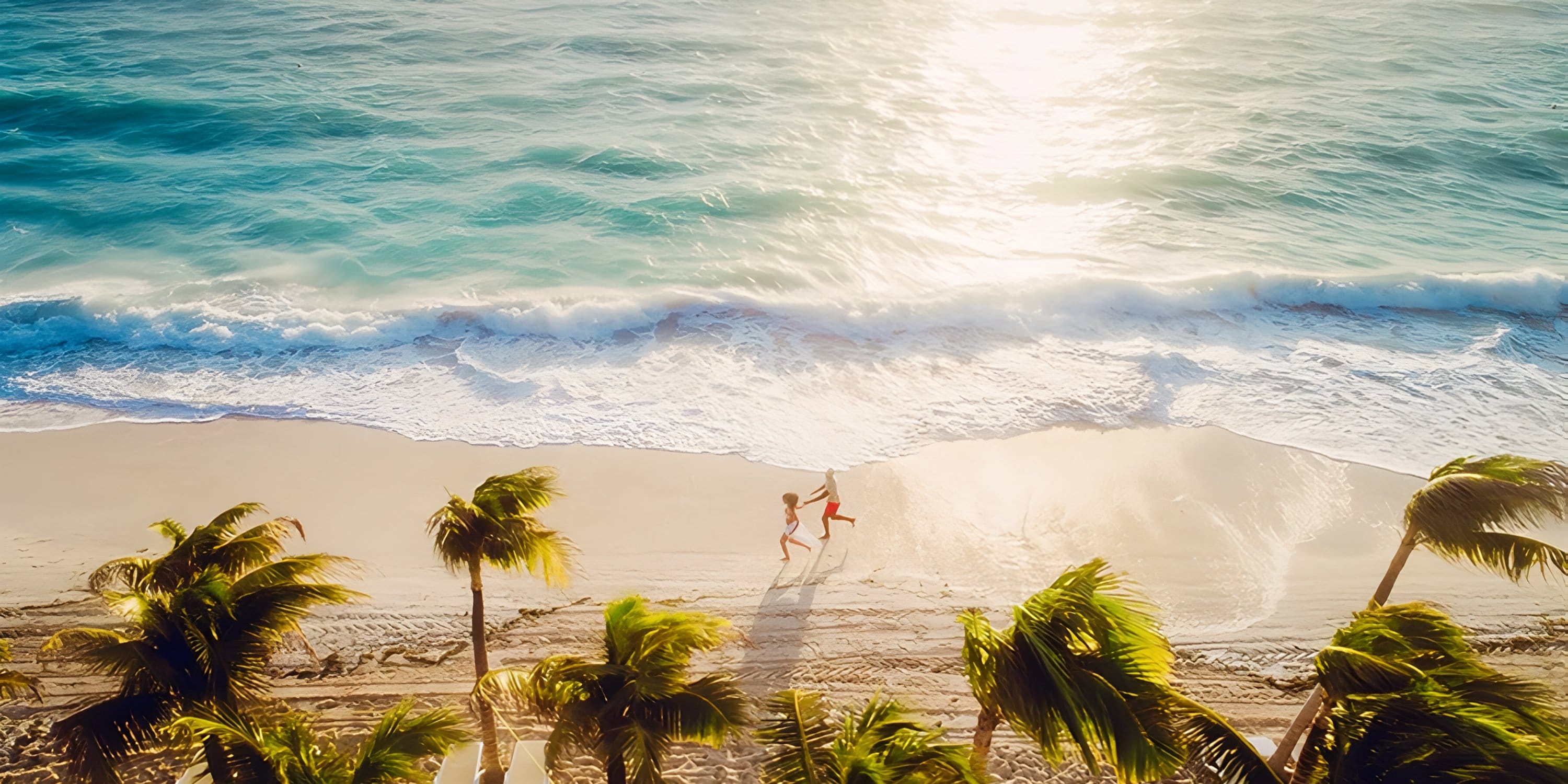 Two people run on a beach by Hotel Riu Palace Peninsula, a lovely destination wedding setting.