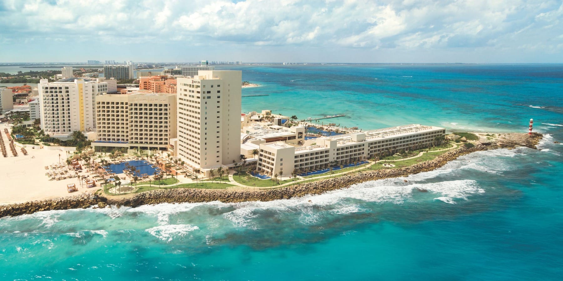 Aerial view of oceanfront resort, perfect for a destination wedding, on rocky turquoise coastline.