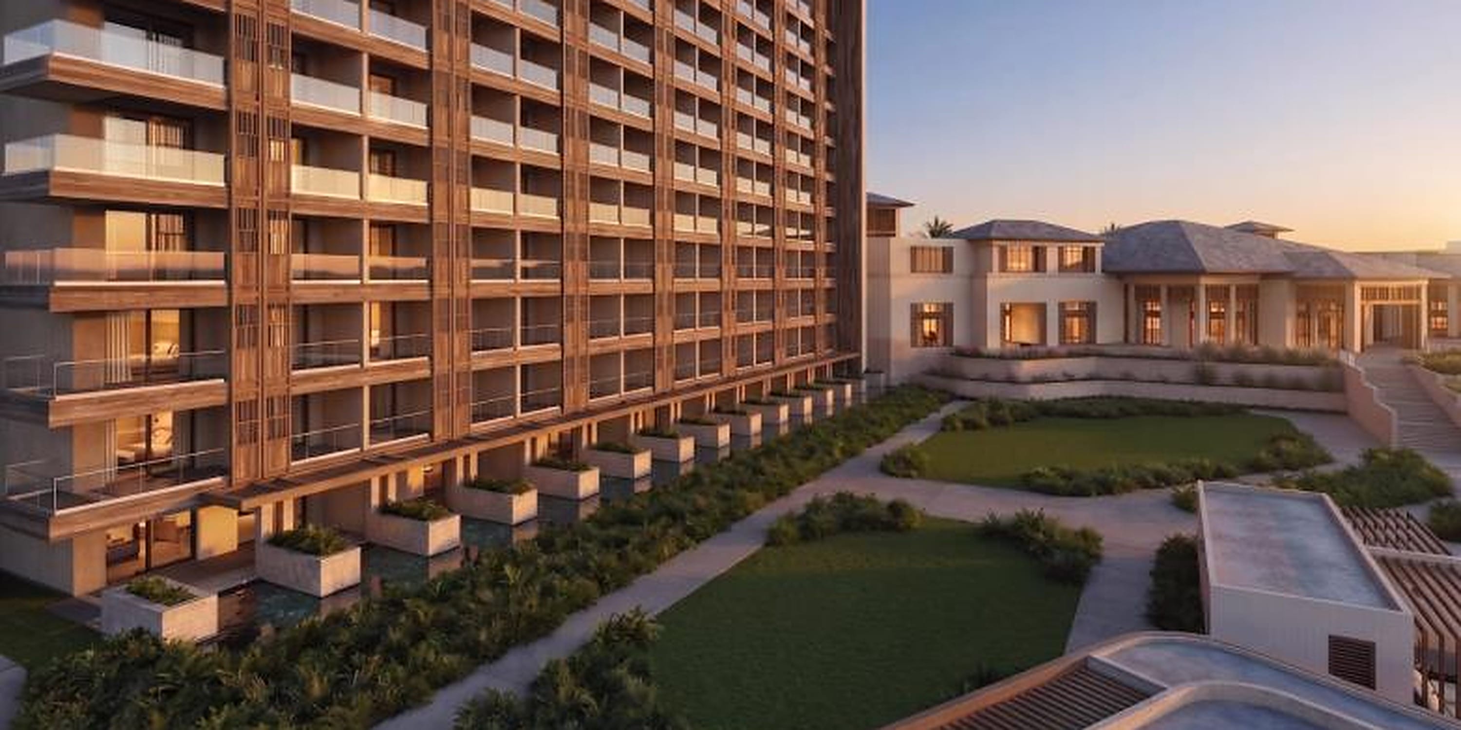 Large multi-story hotel resort with balconies, ideal for a destination wedding, overlooking a lawn.