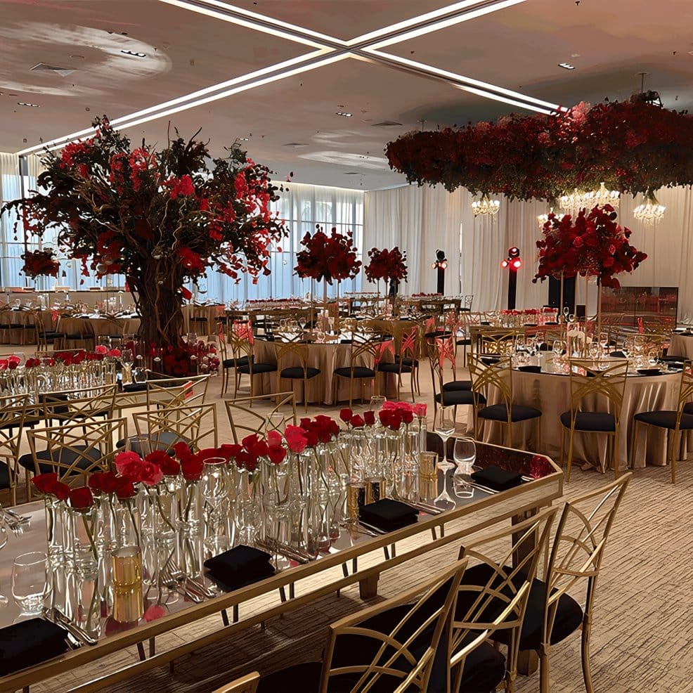 Reception hall with gold chairs and red floral centerpieces for a destination wedding.