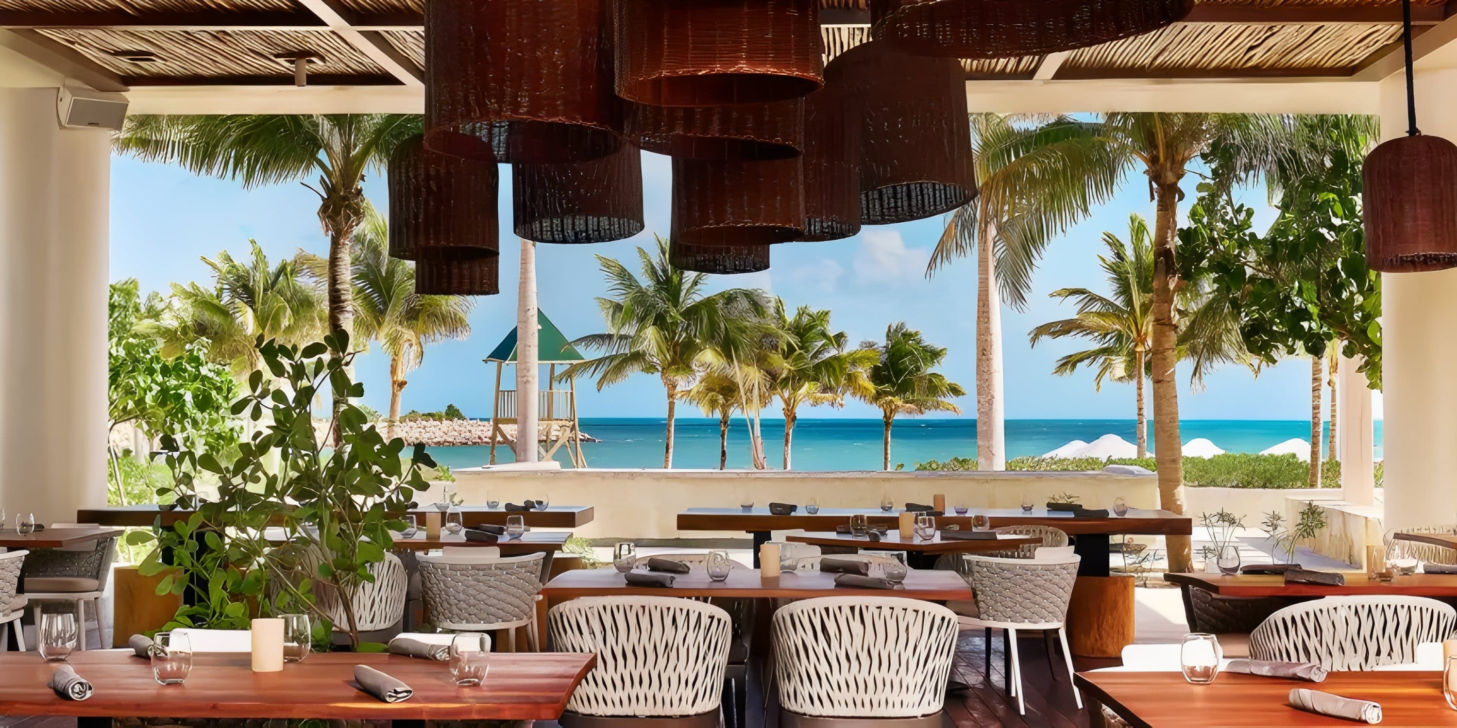 Open-air wedding dining area at Dreams Playa Mujeres overlooking palm trees and the ocean.