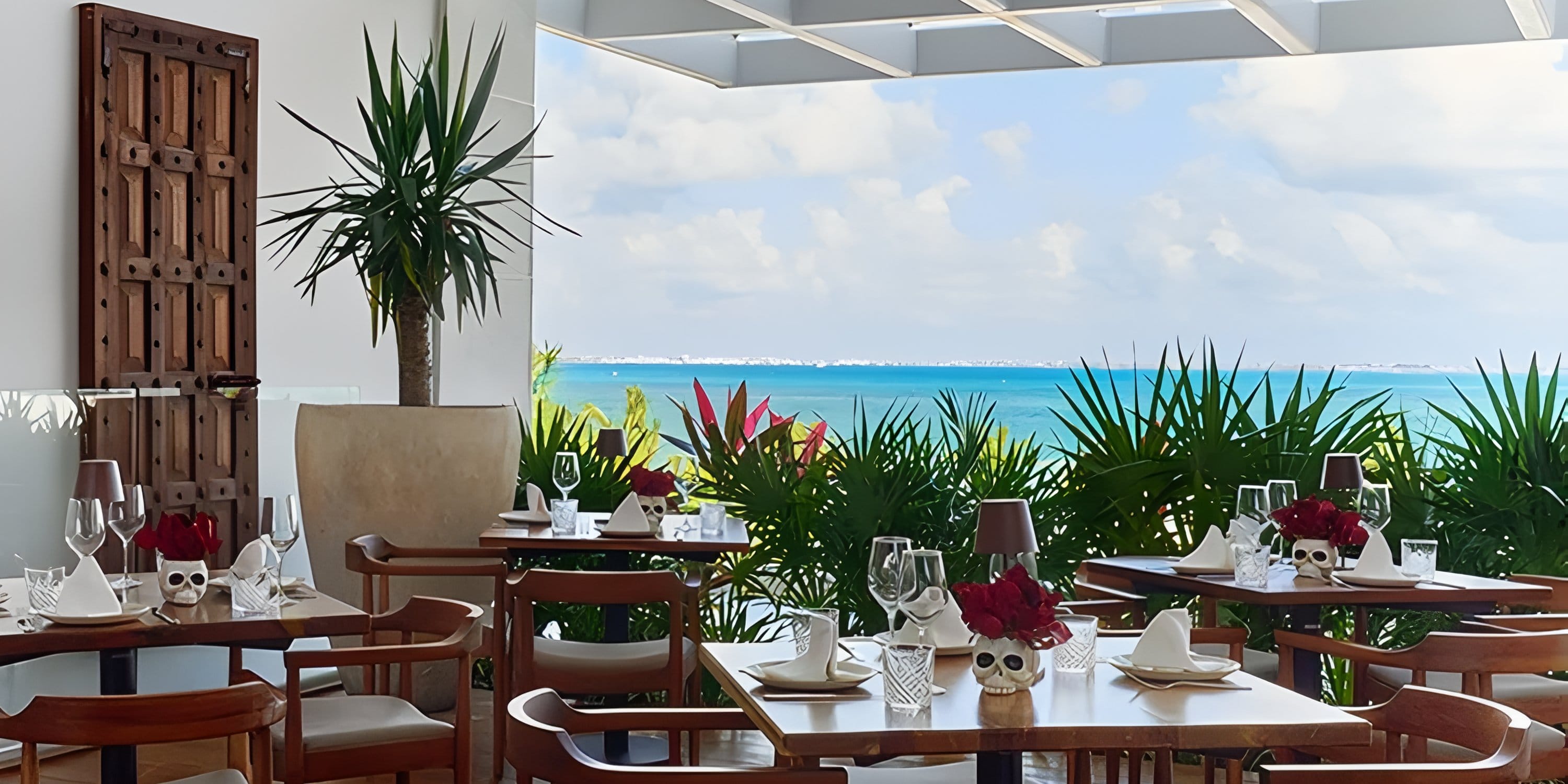 Tables set for a destination wedding on a Dreams Playa Mujeres balcony overlooking the ocean.