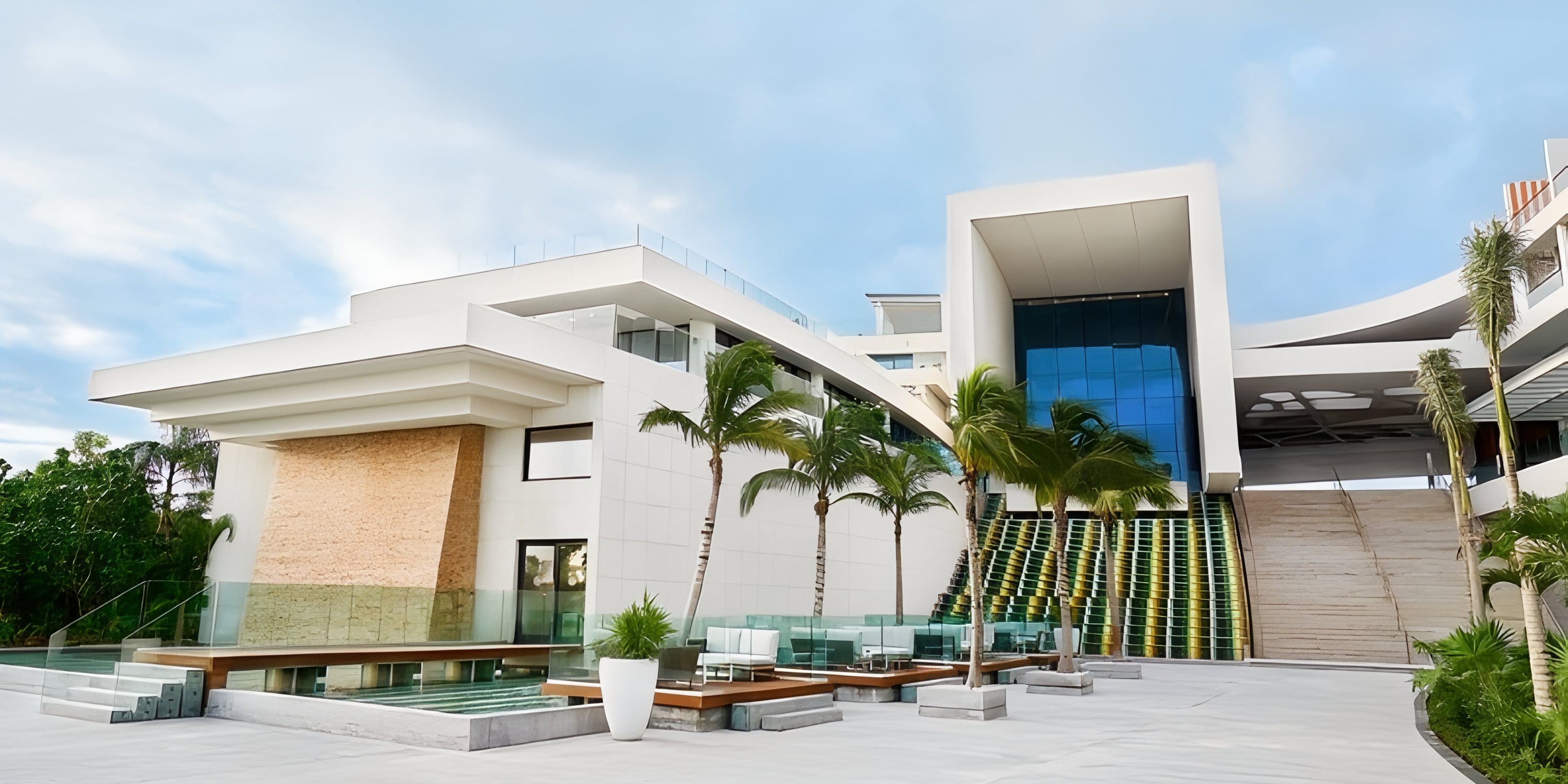Modern white SLS Playa Mujeres resort with palm trees and a lounge area, perfect for a wedding.