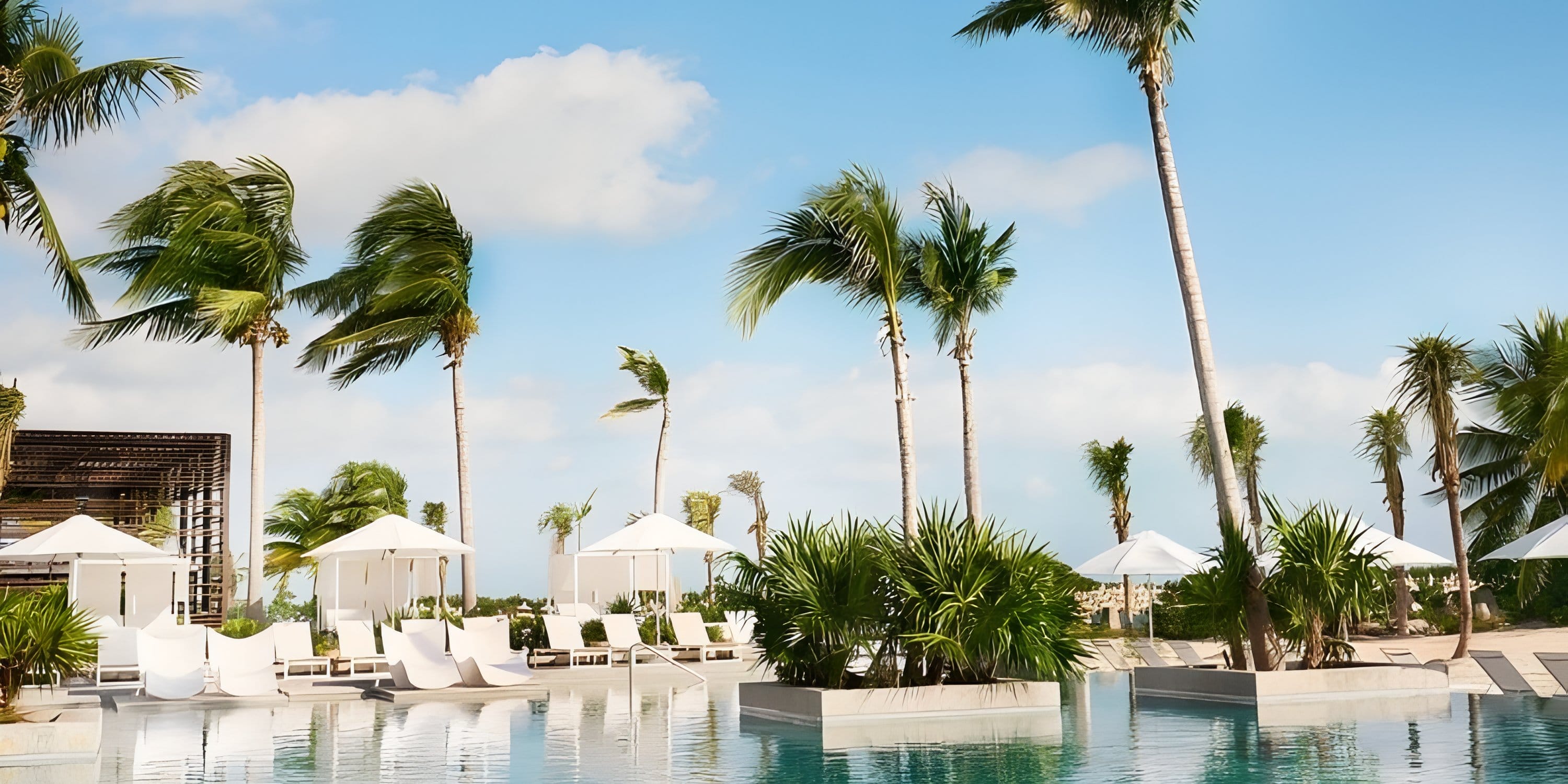 Swimming pool with lounge chairs and umbrellas at an SLS Playa Mujeres destination wedding.