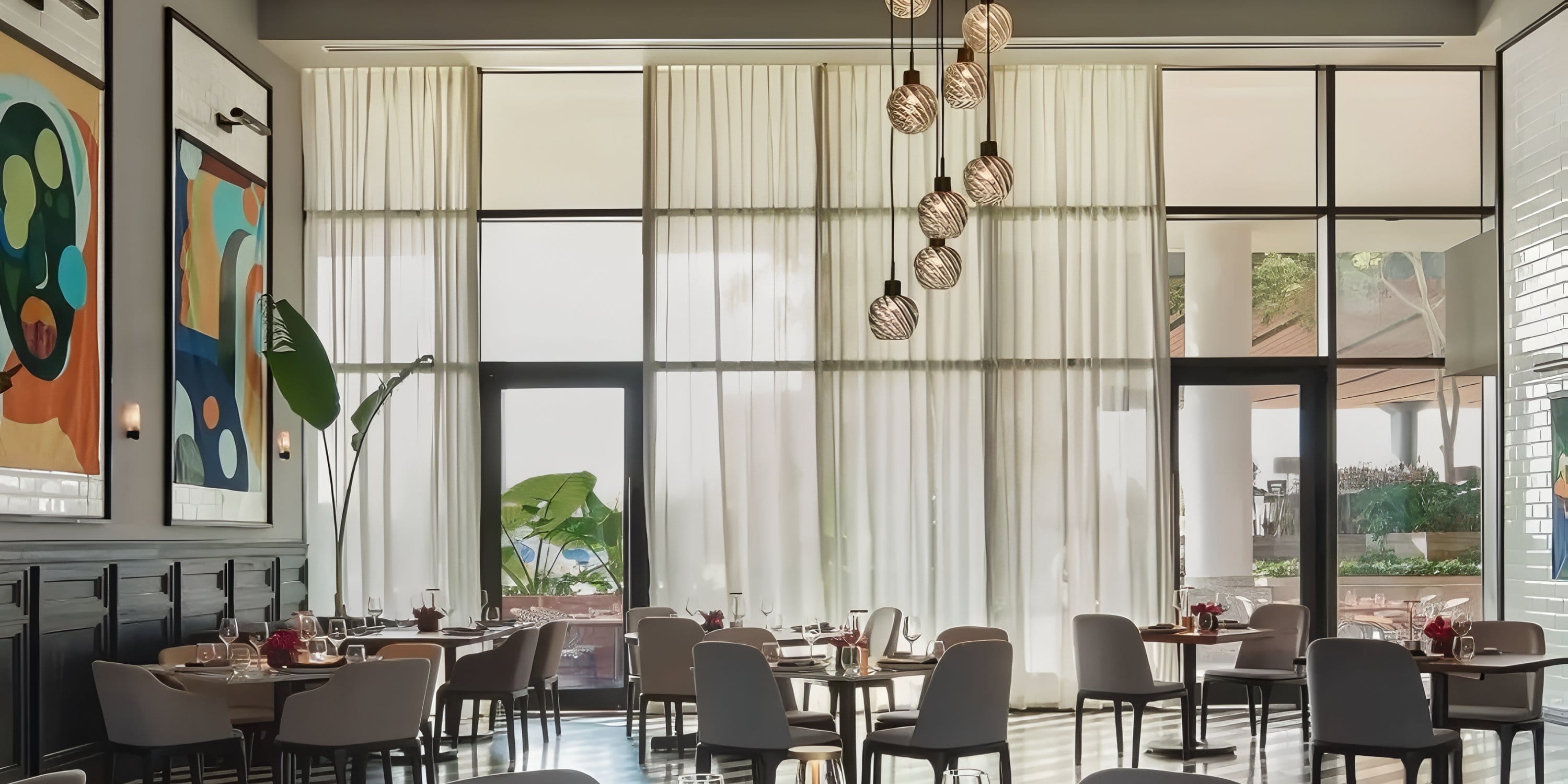 Dining area at Dreams Playa Mujeres set for a destination wedding, with large windows and pendants.