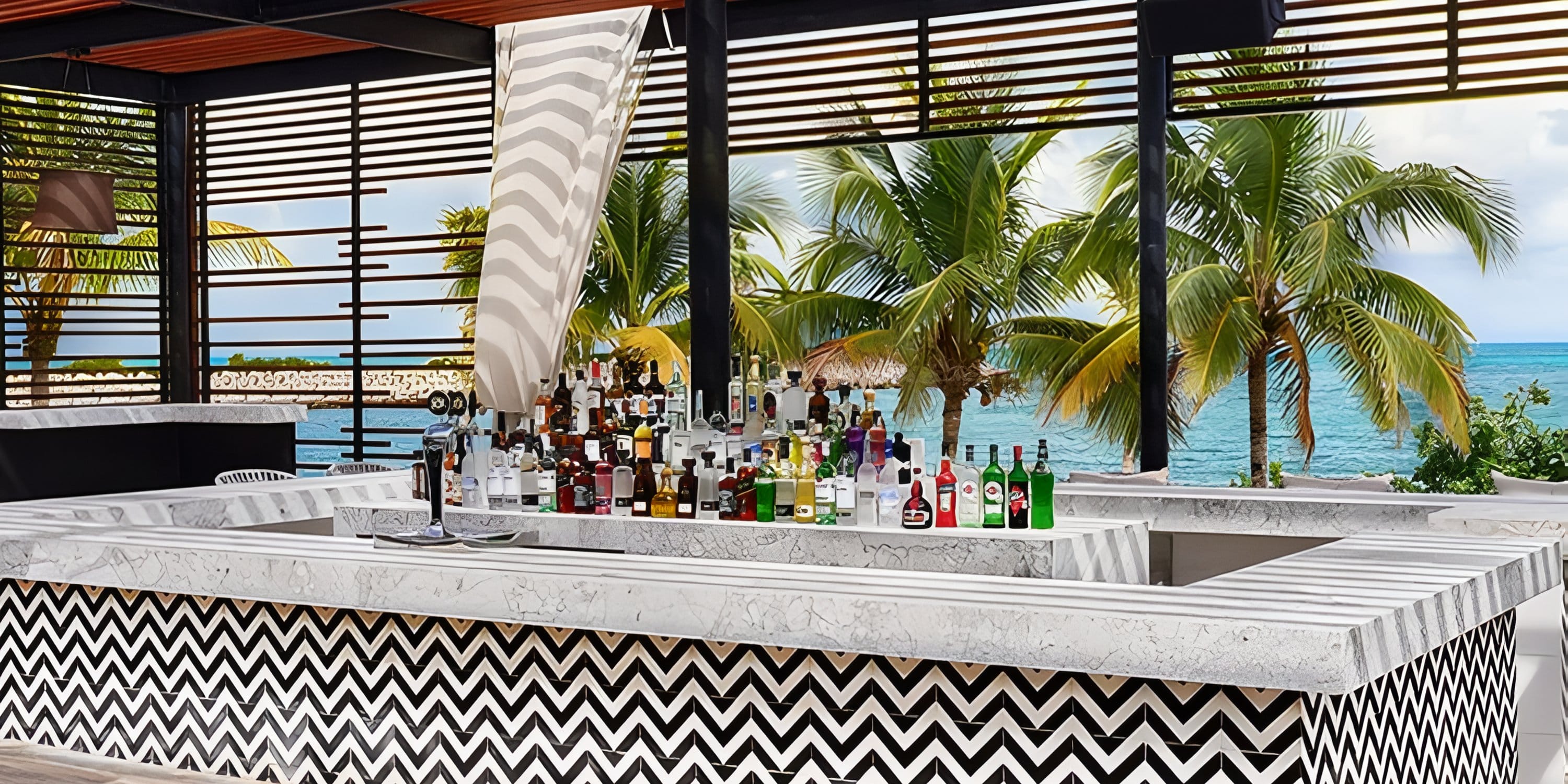Outdoor bar with marble counter and liquor bottles at a Dreams Playa Mujeres destination wedding.