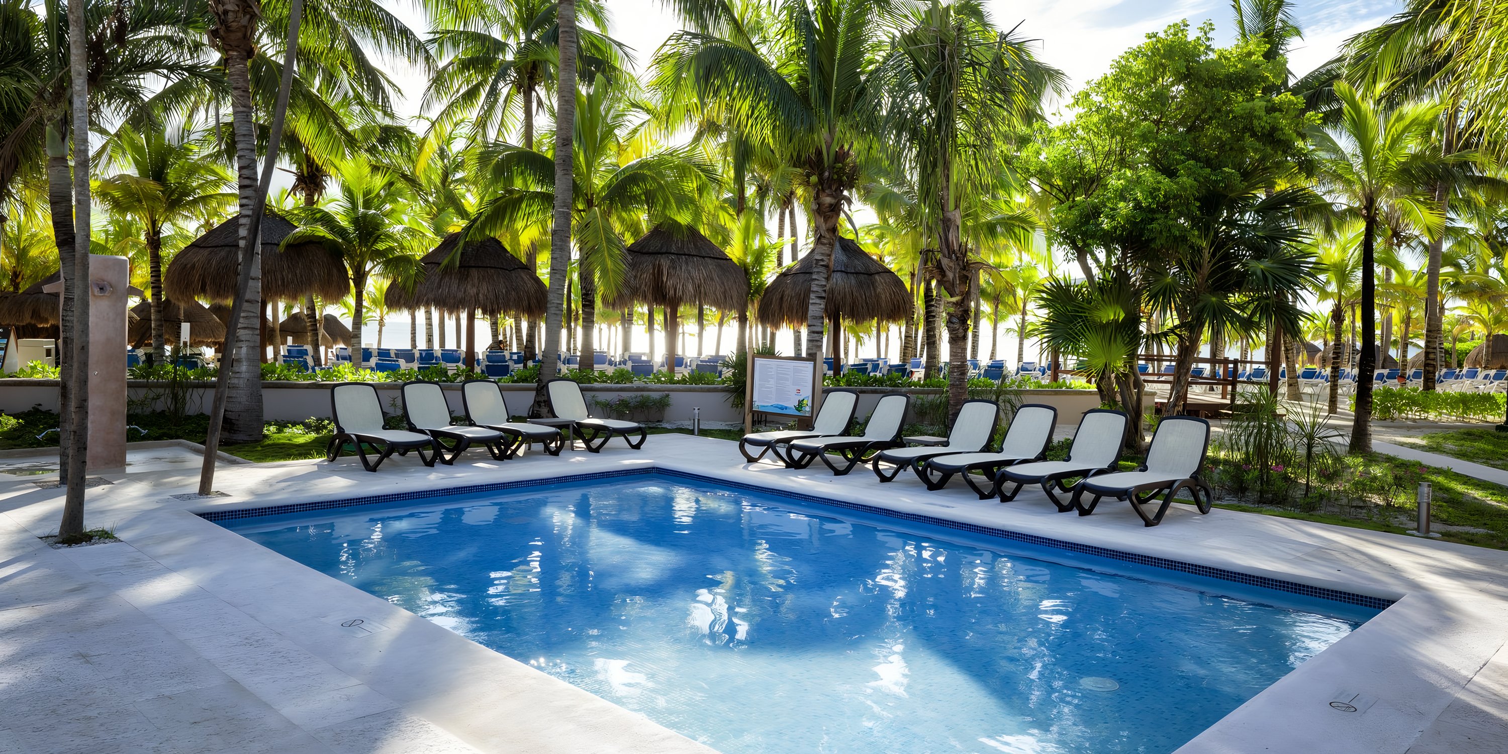 Lounge chairs arranged for a destination wedding by the Viva Maya by Wyndham pool.