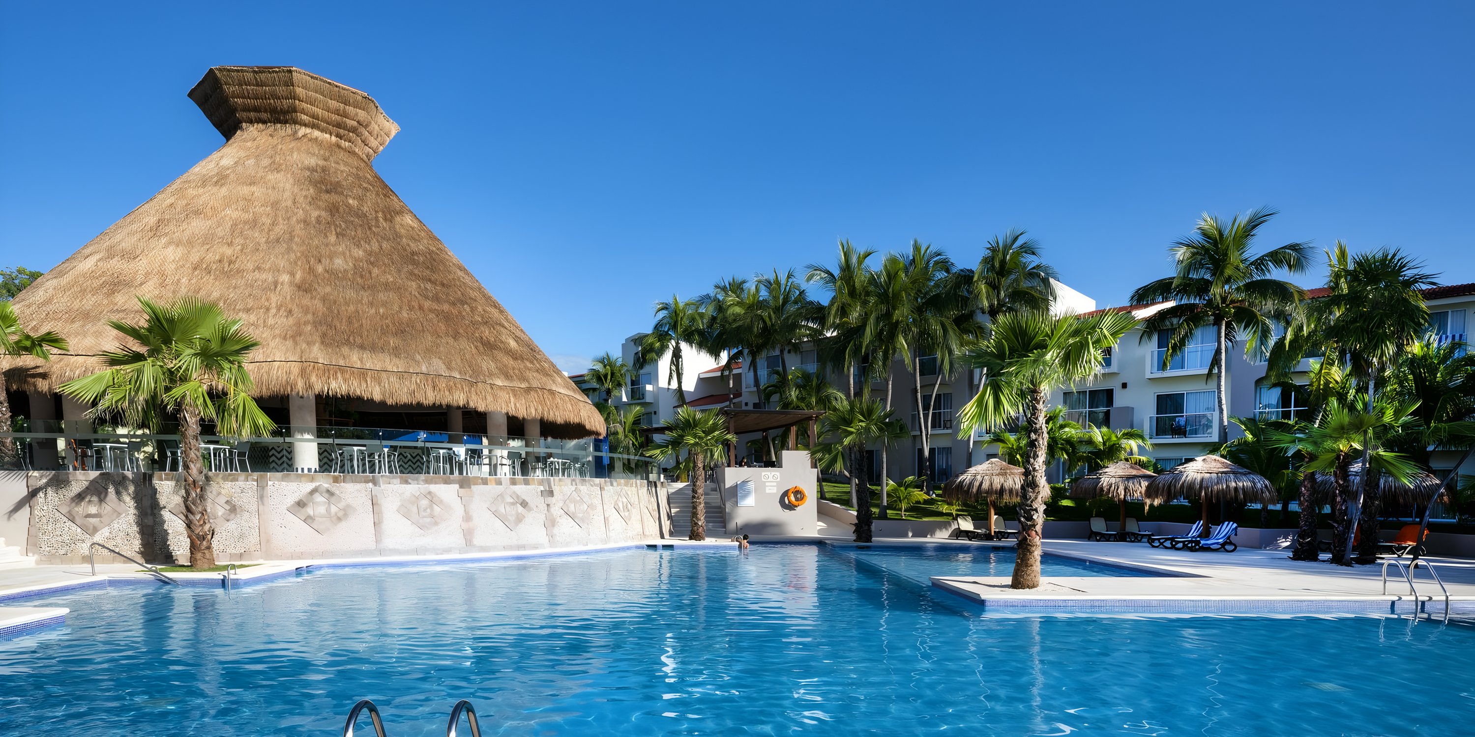 Thatched-roof building beside a pool at Viva Maya, a perfect destination wedding resort.