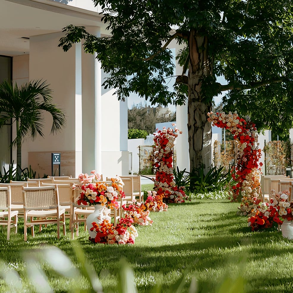 Outdoor destination wedding ceremony with floral arches and seating on a grassy lawn.